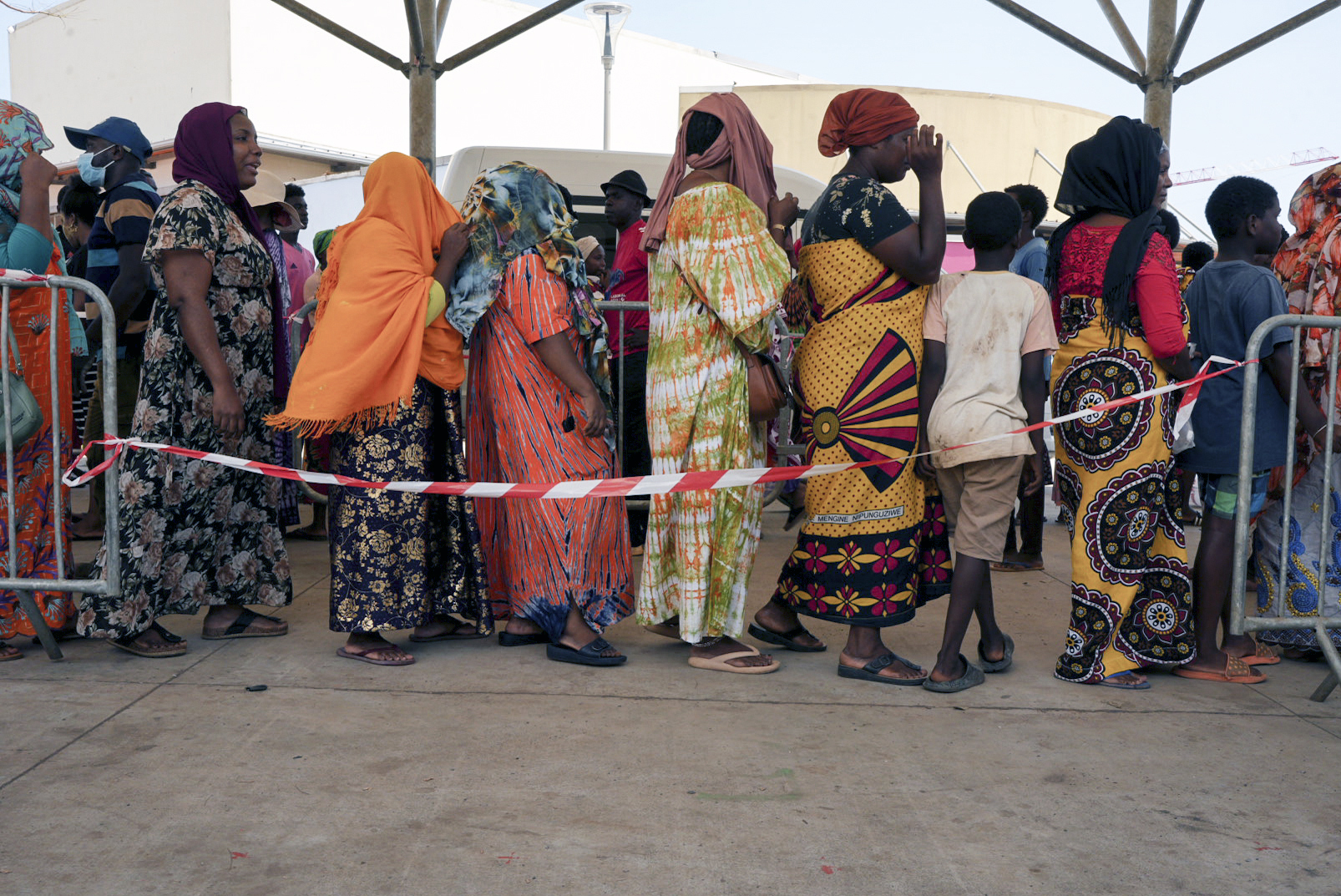 Women wait in line at a water distribution point in Mamoudzou, Mayotte, Saturday, Dec. 21, 2024. (AP Photo/Adrienne Surprenant)