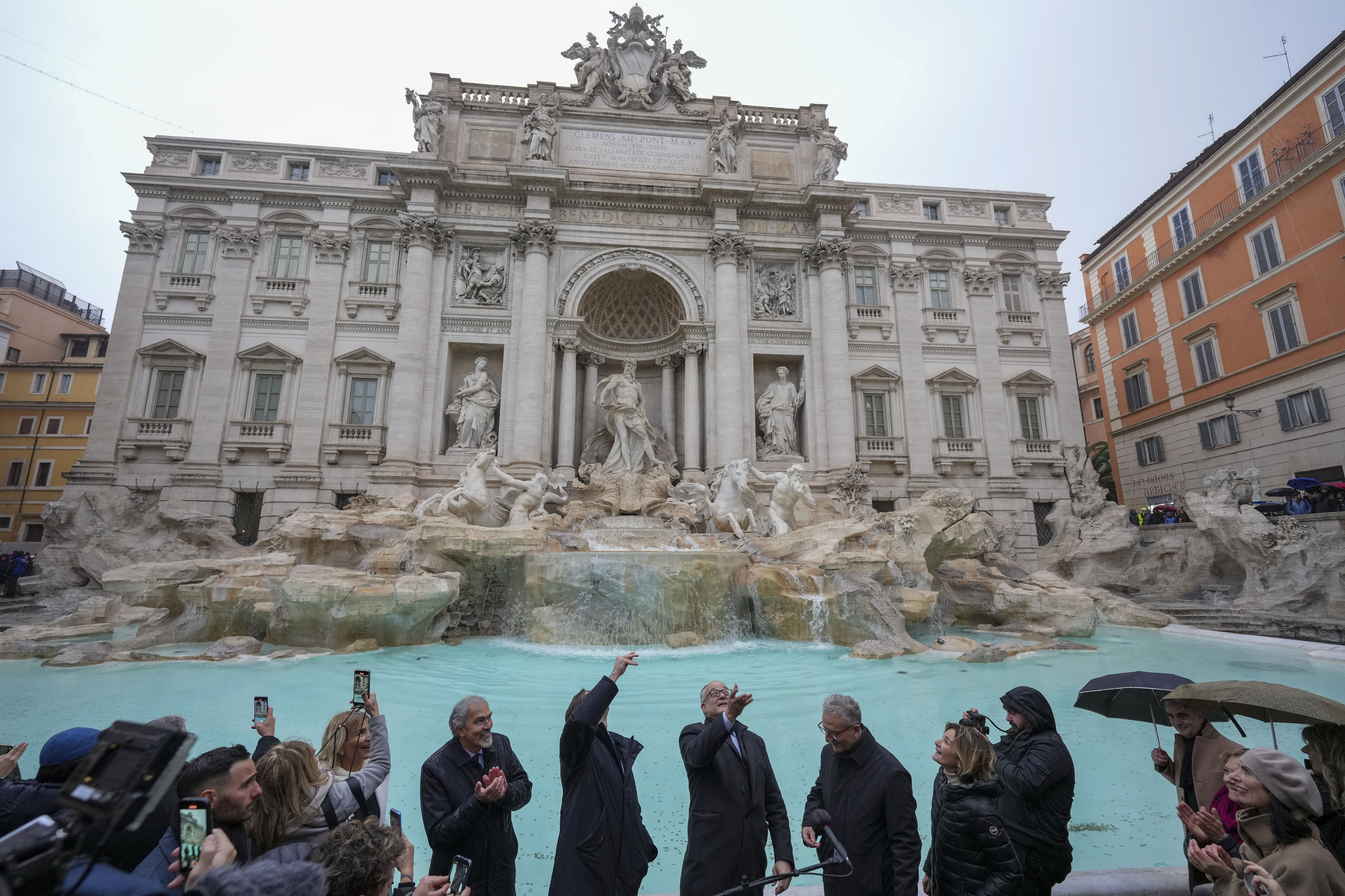 Rome's mayor Roberto Gualtieri, center, tosses a coin into the 18th century Trevi Fountain, one of Rome's most iconic landmarks, as it reopens to the public after undergoing maintenance, just on time for the start of the Jubilee Year, an event expected to draw millions of visitors to the Eternal City, in Rome, Sunday, Dec. 22, 2024. (AP Photo/Andrew Medichini)