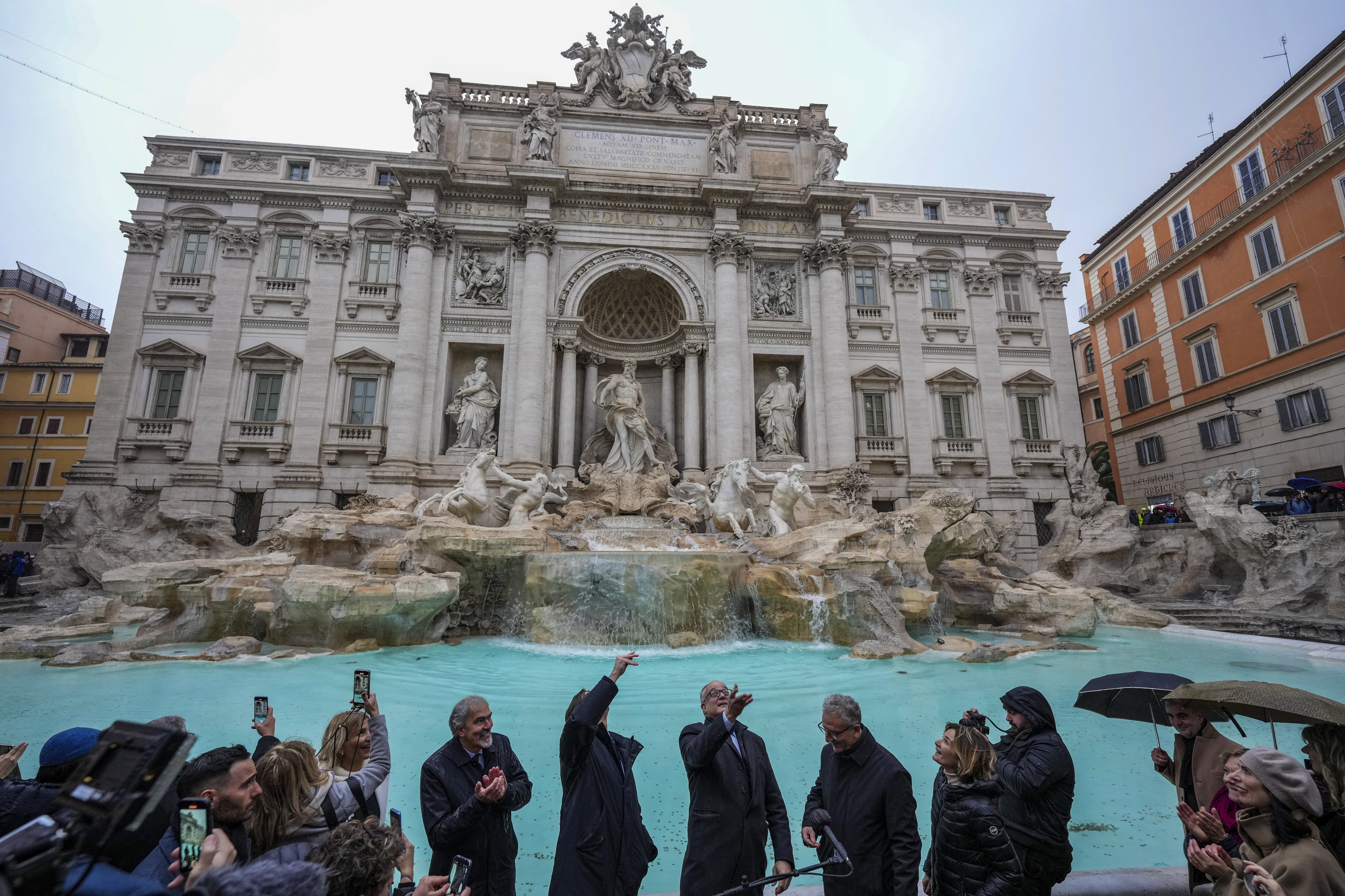 FILE - Rome's mayor Roberto Gualtieri, center, tosses a coin into the 18th century Trevi Fountain, one of Rome's most iconic landmarks, as it reopens to the public after undergoing maintenance, just on time for the start of the Jubilee Year, an event expected to draw millions of visitors to the Eternal City, in Rome, Sunday, Dec. 22, 2024. (AP Photo/Andrew Medichini, File)