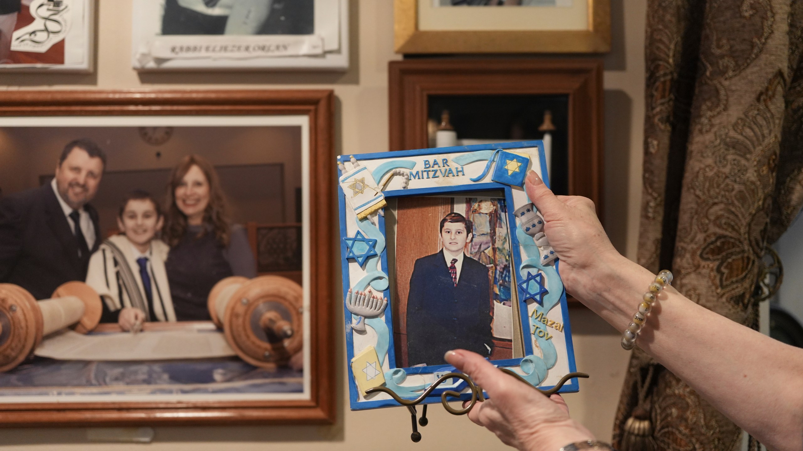 Debbie Marcus shows a framed photo of her son, Dov Marcus, taken at his Bar Mitzvah on display at their family home in Teaneck, N.J., on Friday, Dec. 20, 2024. (AP Photo/Luis Andres Henao)