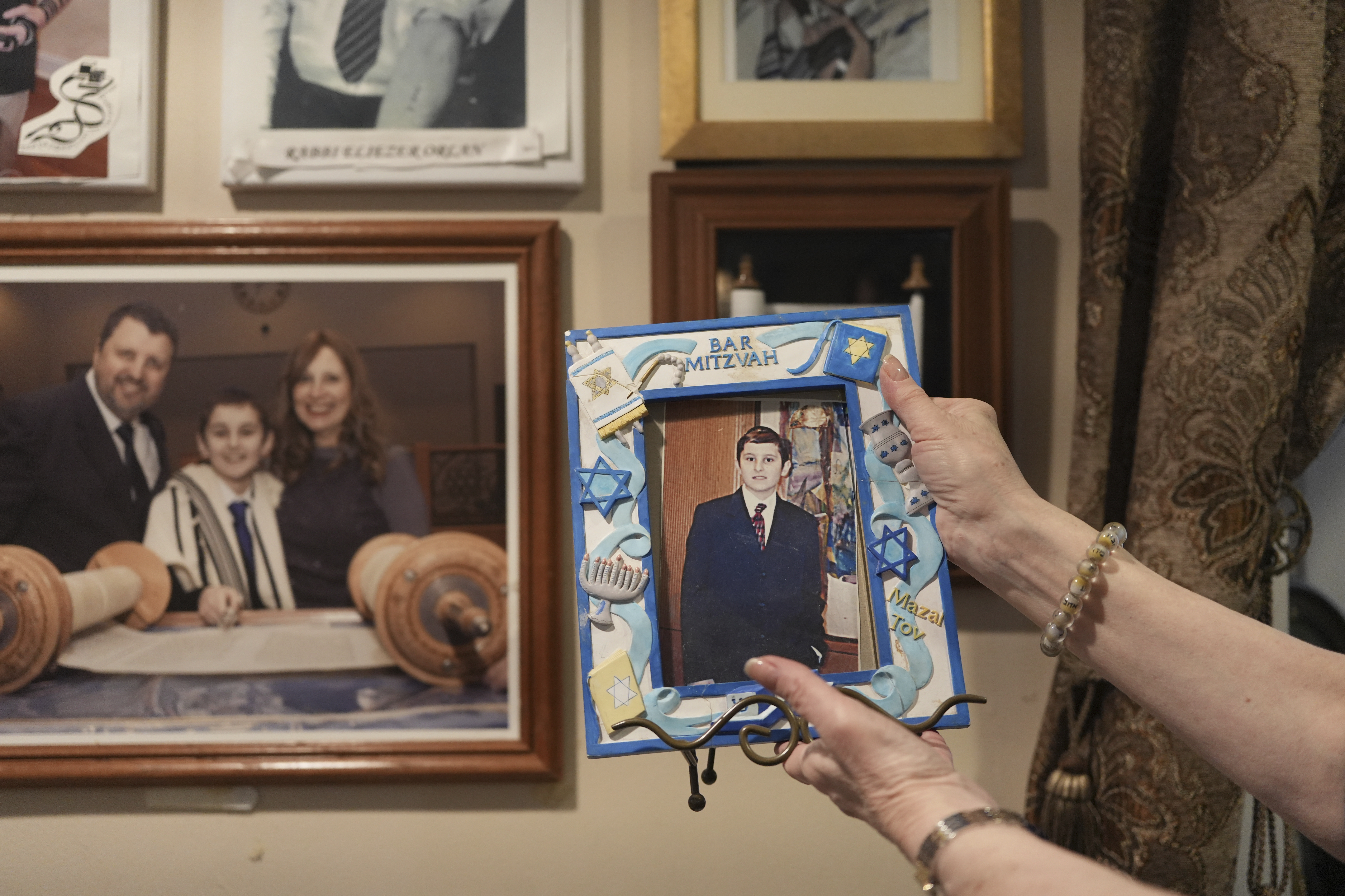 Debbie Marcus shows a framed photo of her son, Dov Marcus, taken at his Bar Mitzvah on display at their family home in Teaneck, N.J., on Friday, Dec. 20, 2024. (AP Photo/Luis Andres Henao)