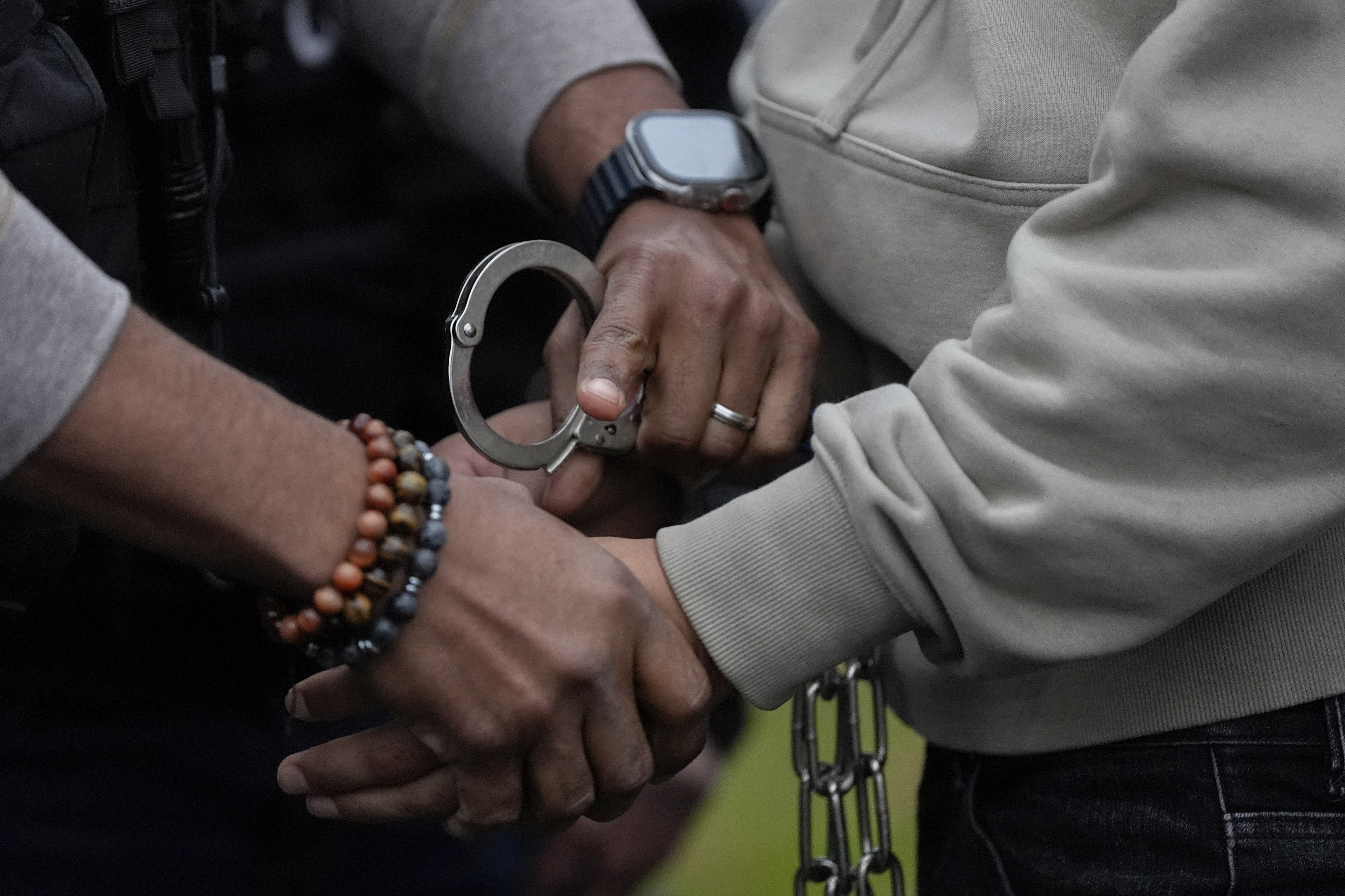 A deportation officer with Enforcement and Removal Operations in U.S. Immigration and Customs Enforcement's New York City field office changes the handcuffs of Wilmer Patricio Medina-Medina from back to front after arresting him during an early morning operation, Tuesday, Dec. 17, 2024, in the Bronx borough of New York. (AP Photo/Julia Demaree Nikhinson)