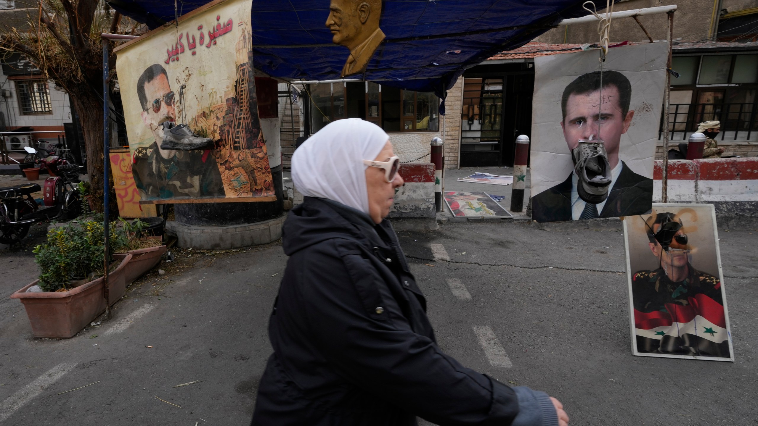 Shoes hanging in front of portraits of ousted Syrian President Bashar Assad in Damascus, Syria, Monday, Dec. 23, 2024. (AP Photo/Hussein Malla)