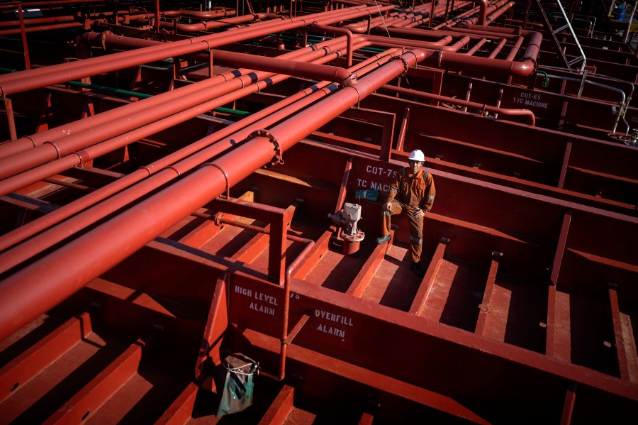 Rahil Gunawan, 55, of Indonesia, poses on the deck of the chemical tanker on which he works as a deckhand while calling at the port of Barcelona, Spain, Friday, Sept. 27, 2024. Gunawan, who has five children and has been working on cargo ships for more than 25 years, spends seven to ten months at sea per year. (AP Photo/Emilio Morenatti)