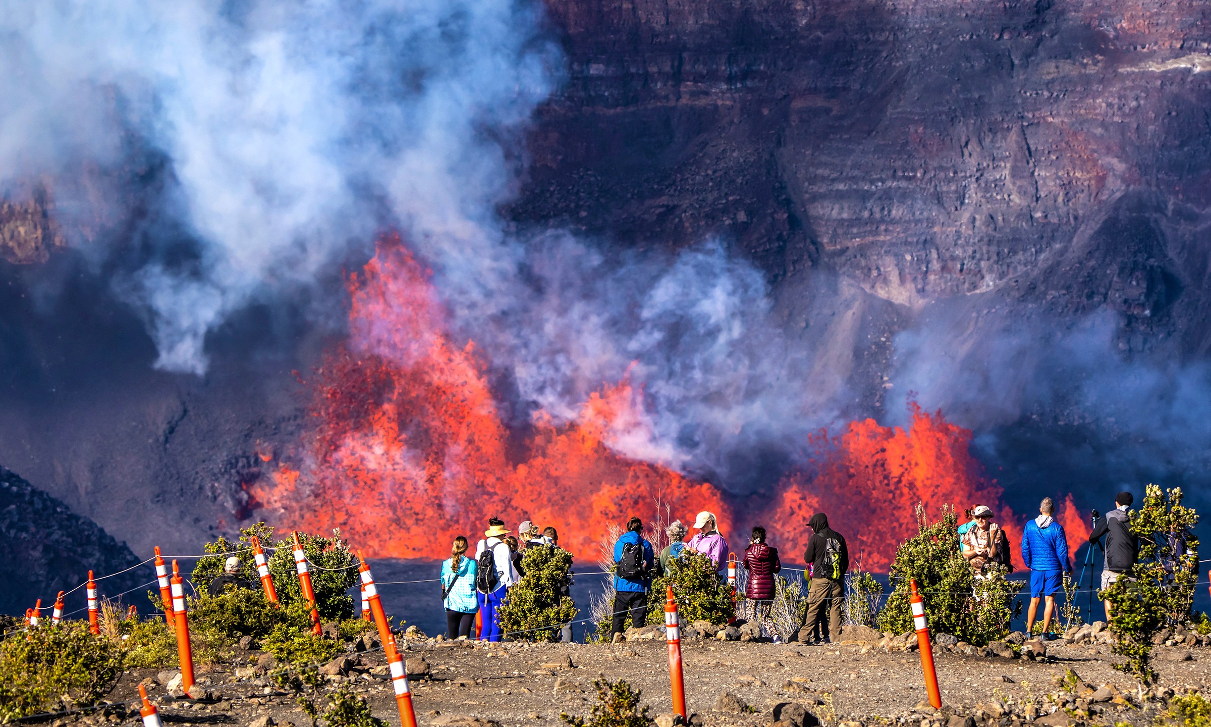 In this photo provided by the National Park Service, people watch as an eruption takes place on the summit of the Kilauea volcano in Hawaii, Monday, Dec. 23, 2024. (Janice Wei/NPS via AP)