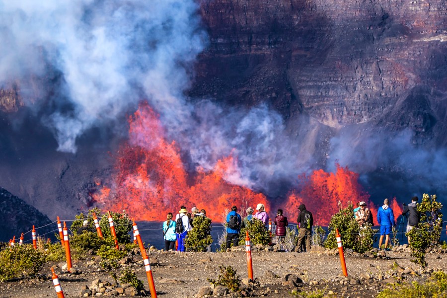 In this photo provided by the National Park Service, people watch as an eruption takes place on the summit of the Kilauea volcano in Hawaii, Monday, Dec. 23, 2024. (Janice Wei/NPS via AP)