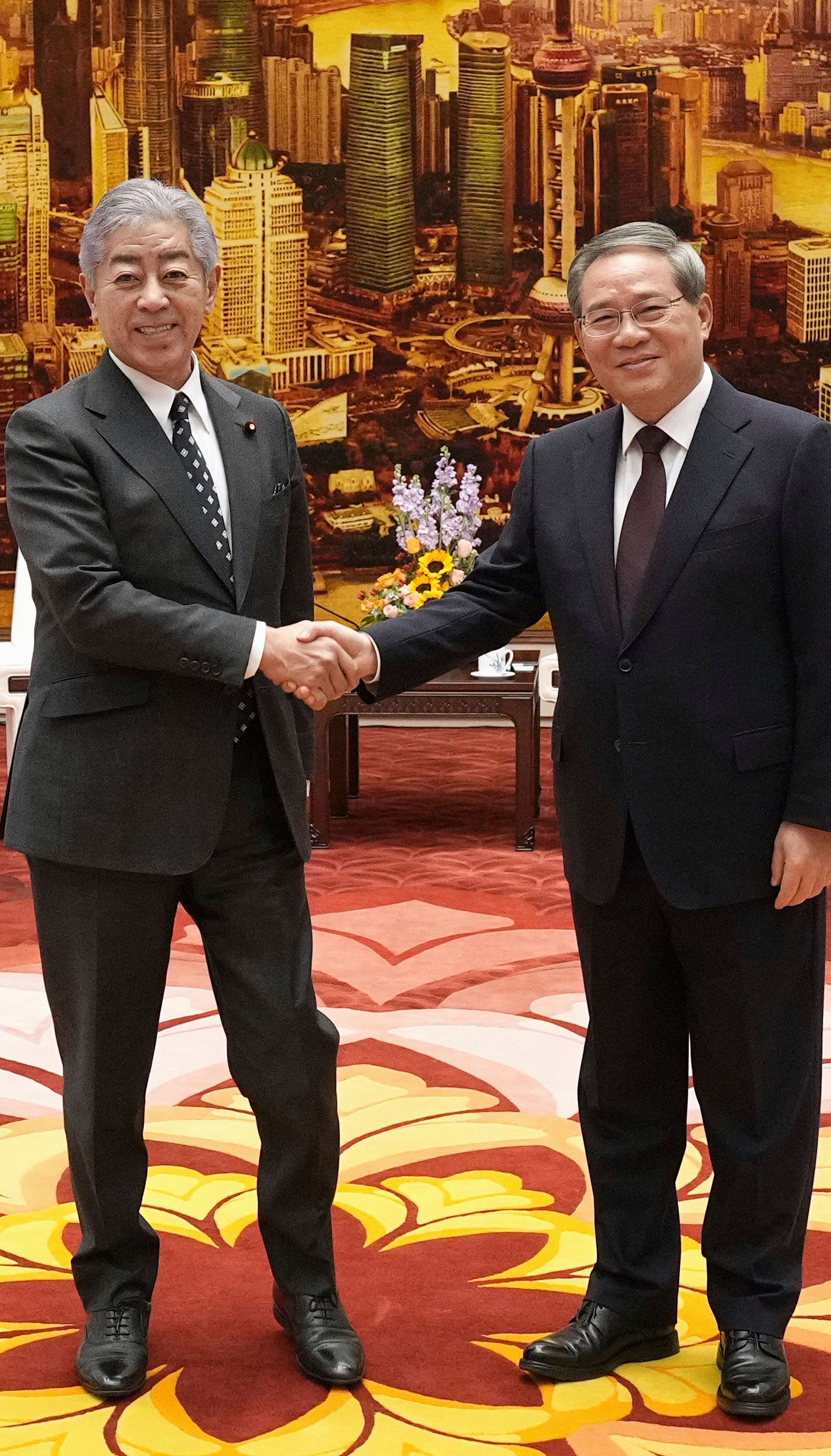 Japan's Foreign Minister Takeshi Iwaya, left, and Chinese Premier Li Qiang, right, shake hands at the Great Hall of the People in Beijing Wednesday, Dec. 25, 2024. (Kyodo News via AP)