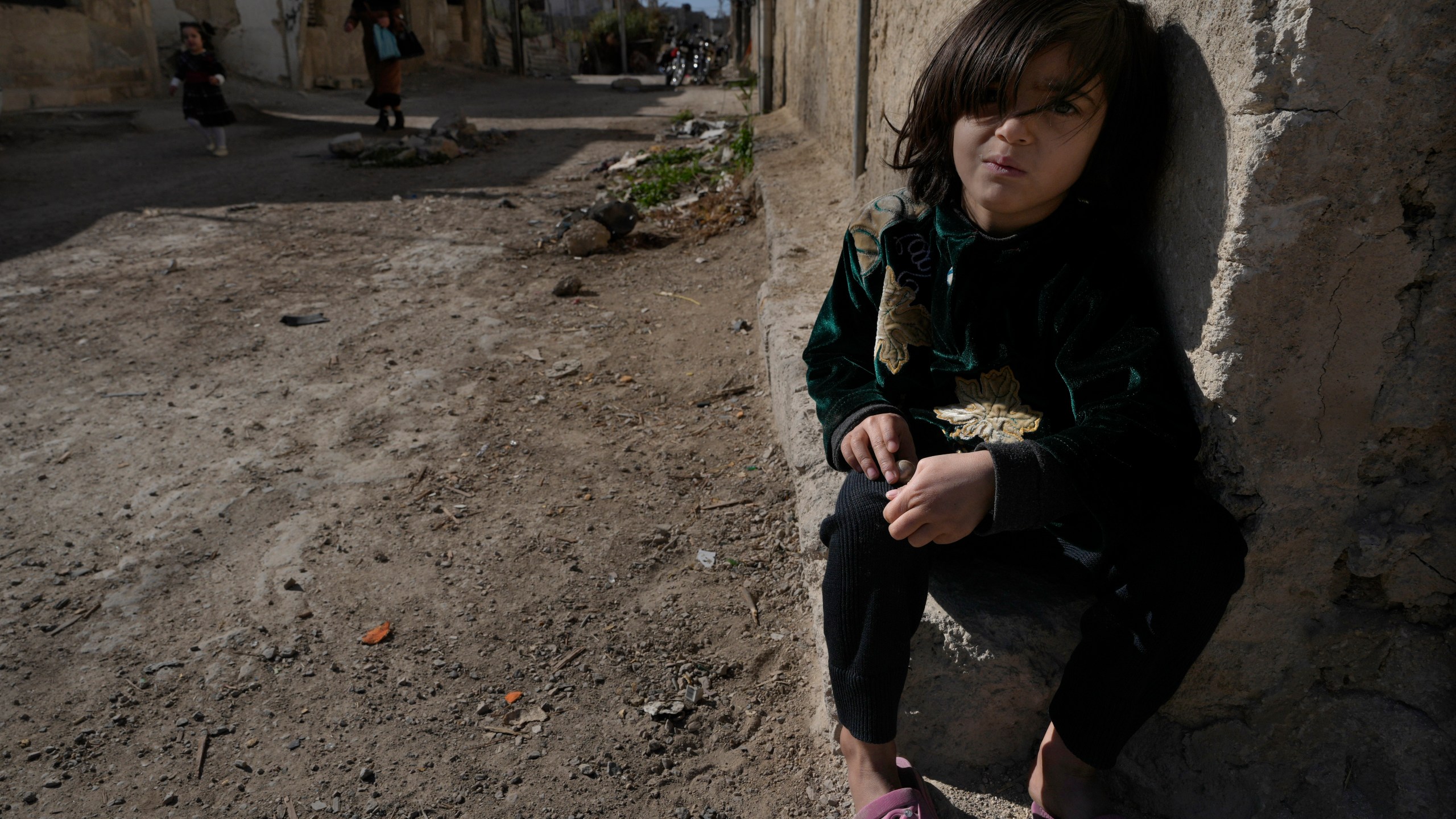 A Syrian girl sits next of her parent house, at an alley that was hit by the sarin struck during a 2013 chemical weapons attack that was blamed on then President Bashar Assad's forces, in Zamalka neighbourhood, on the outskirts of Damascus, Syria, Wednesday, Dec. 25, 2024. (AP Photo/Hussein Malla)