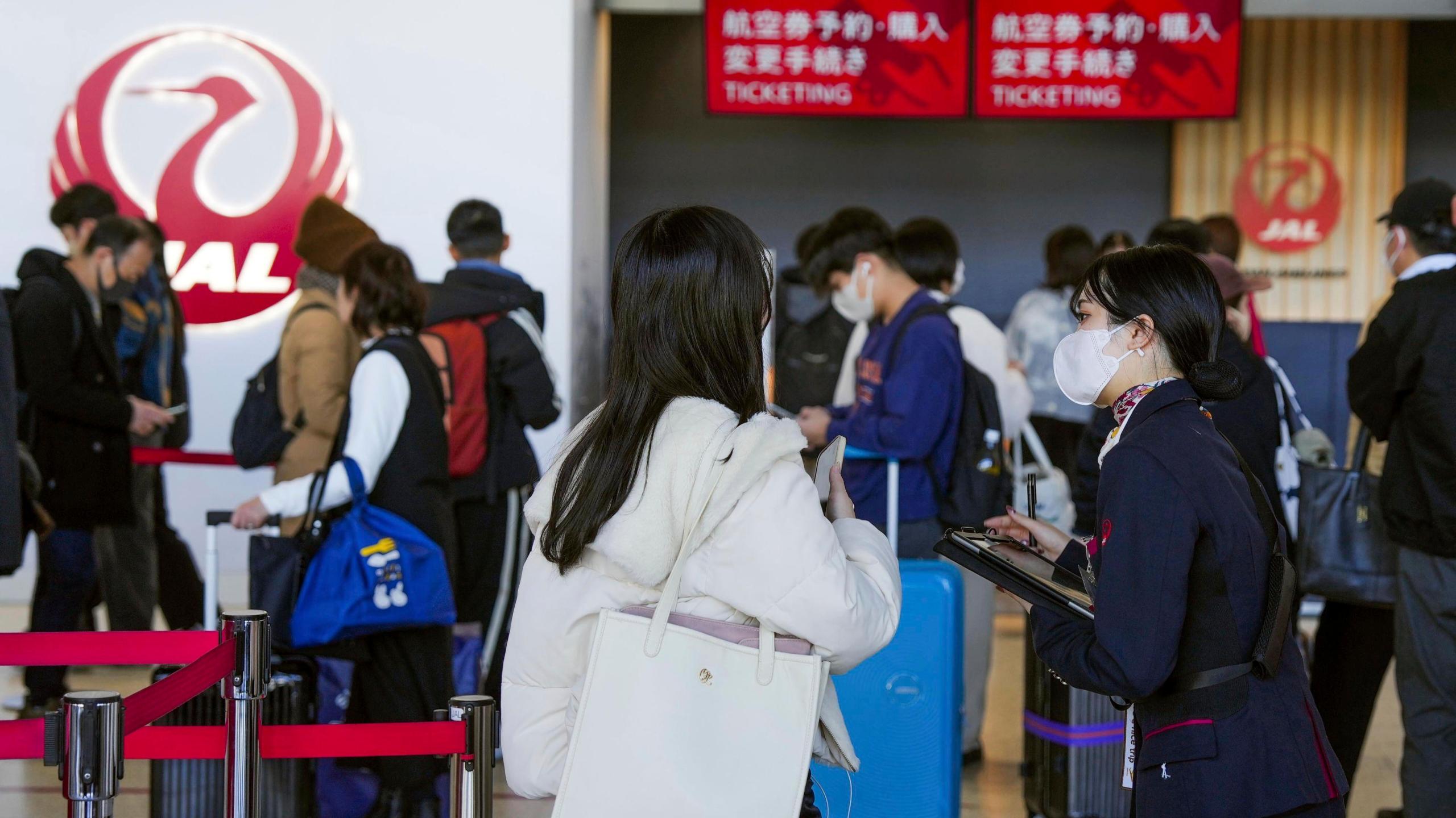 A staff member of Japan Airlines helps customers at Osaka International Airport on the outskirts of Osaka, western Japan, Thursday, Dec. 26, 2024, after the airlines said it was hit by a cyberattack. (Nobuki Ito/Kyodo News via AP)