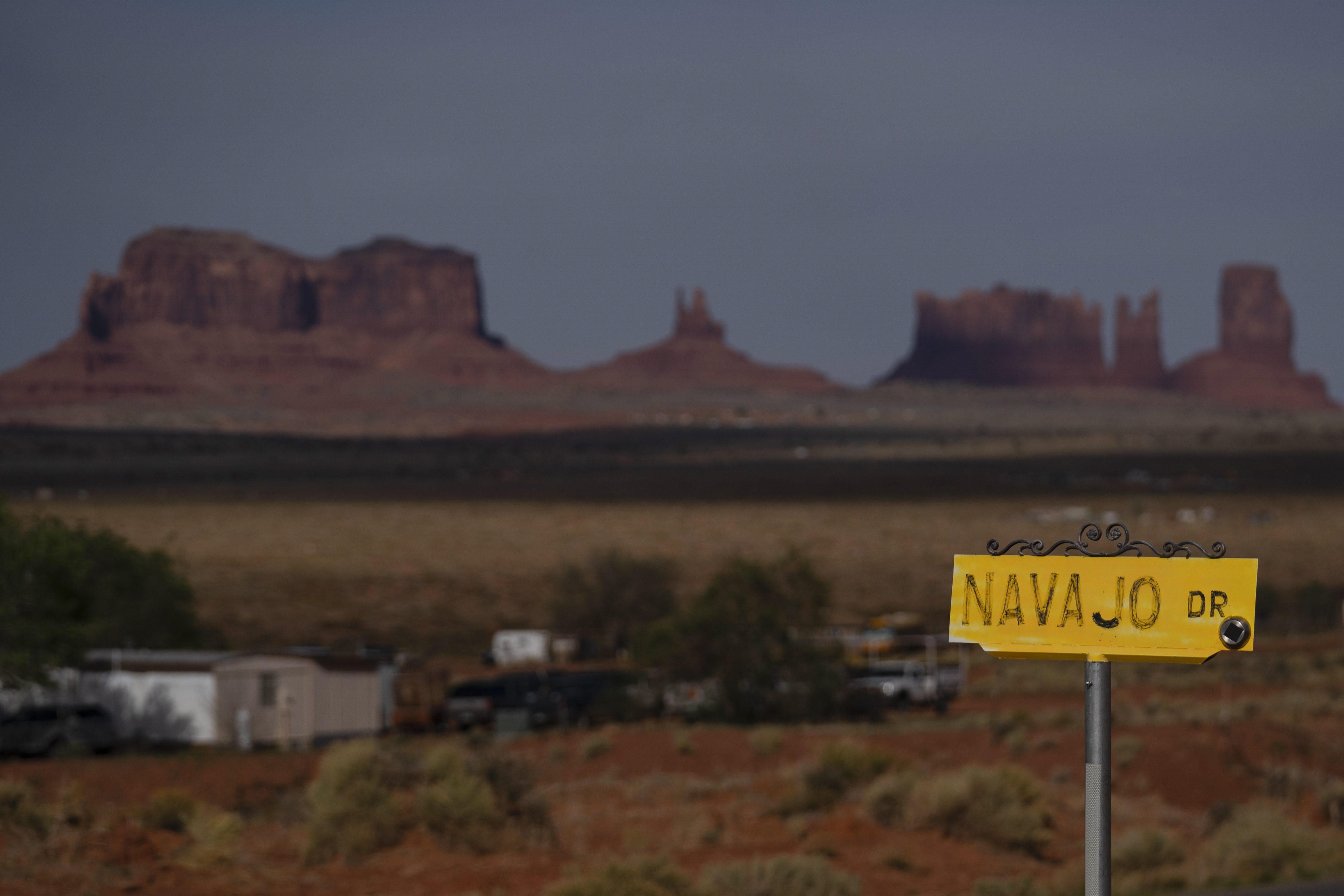 FILE - A sign marks Navajo Drive, as Sentinel Mesa stands in the distance in Oljato-Monument Valley, Utah on the Navajo Reservation, April 30, 2020. (AP Photo/Carolyn Kaster, File)