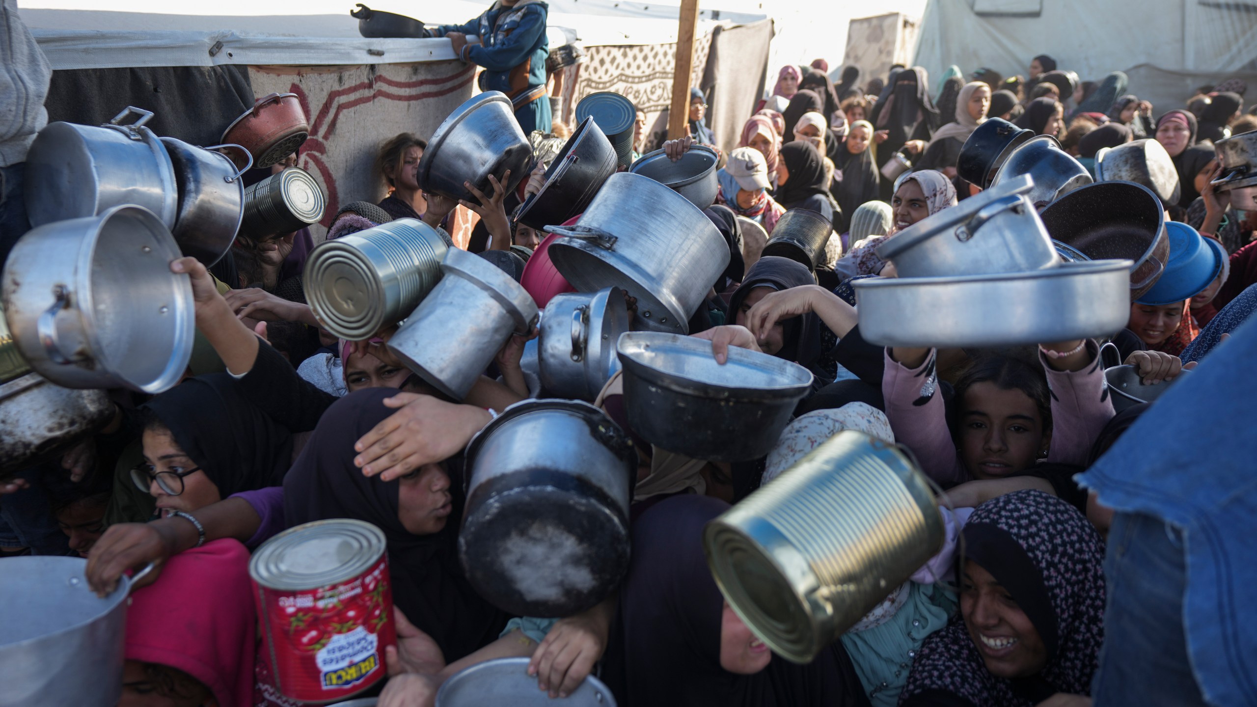 FILE - Palestinian women and girls struggle to reach for food at a distribution center in Khan Younis, Gaza Strip Friday, Dec. 6, 2024. (AP Photo/Abdel Kareem Hana, File)