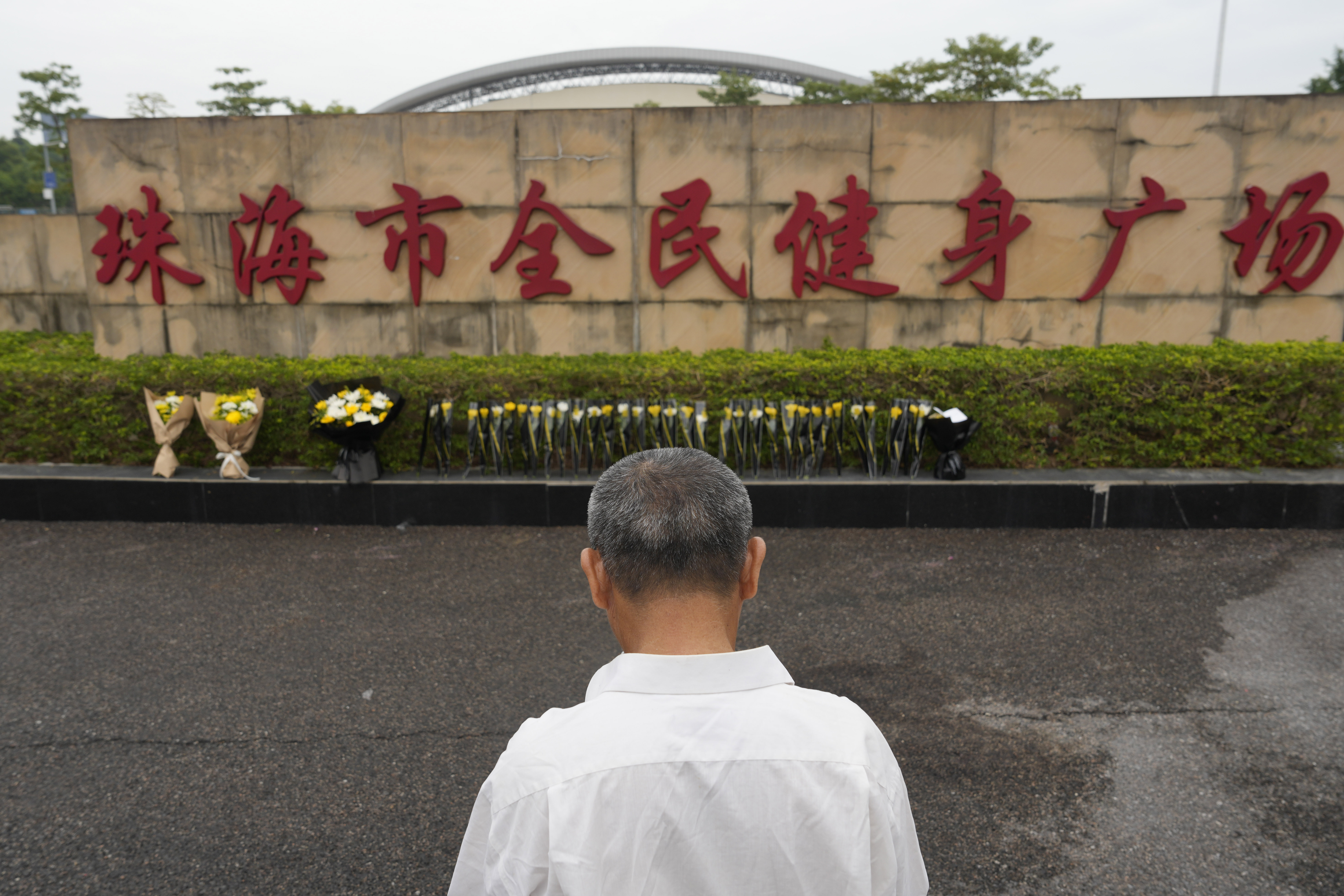 FILE - A man stands near flowers laid outside the "Zhuhai People's Fitness Plaza" where a man rammed his car into people exercising at the sports center, in Zhuhai in southern China's Guangdong province, Nov. 13, 2024. (AP Photo/Ng Han Guan, File)