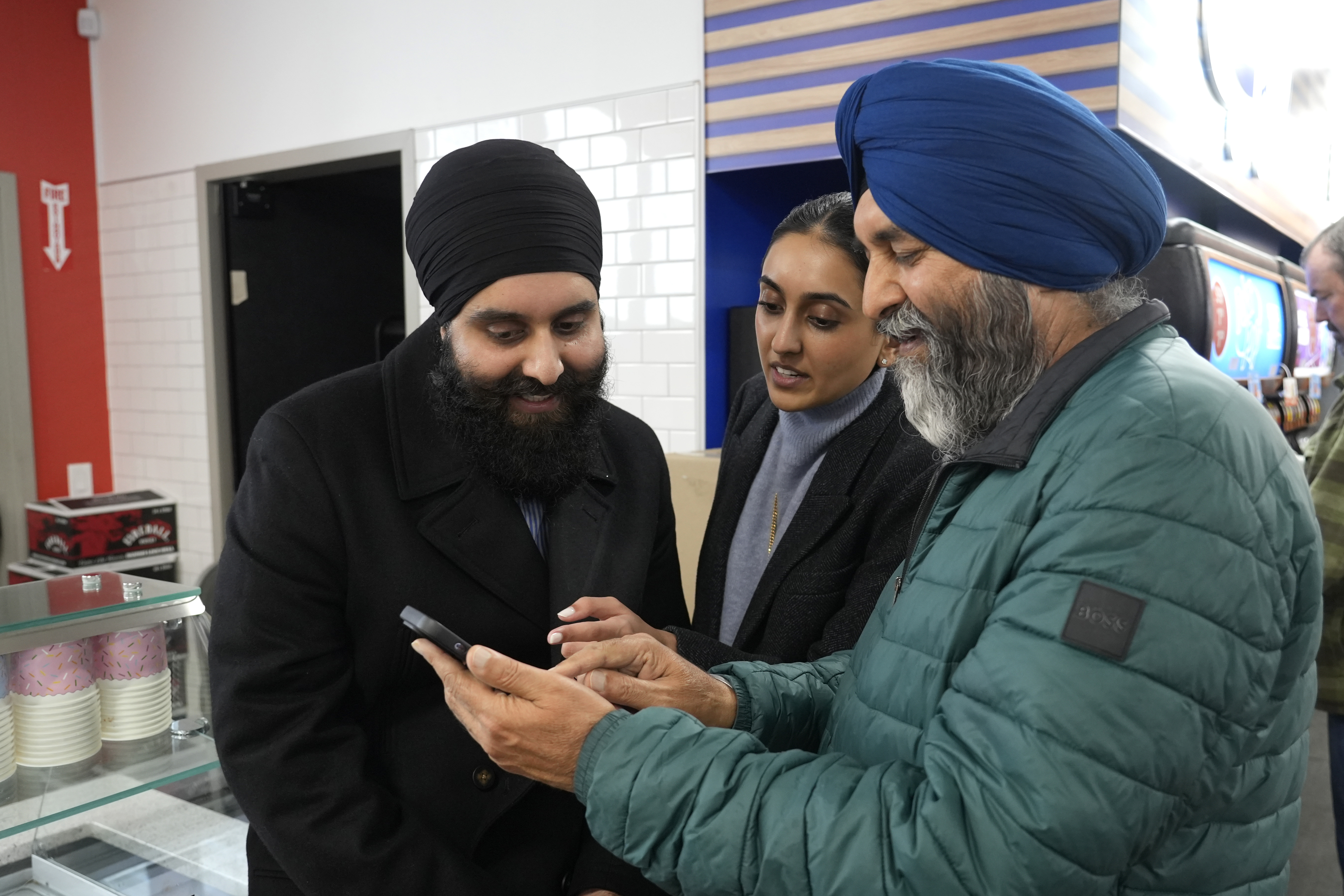 Ishar Gill, left, his sister Verdeen Gill, center and father Jaspal Singh. right, look over congratulatory texts for selling winning the Mega-Million lotto ticket worth an estimated $1.22 billion at the family's store in Cottonwood, Calif., Saturday, Dec. 28, 2024. After three months without anyone winning the top prize in the lottery, the ticket with the winning numbers was drawn Friday night.(AP Photo/Rich Pedroncelli).