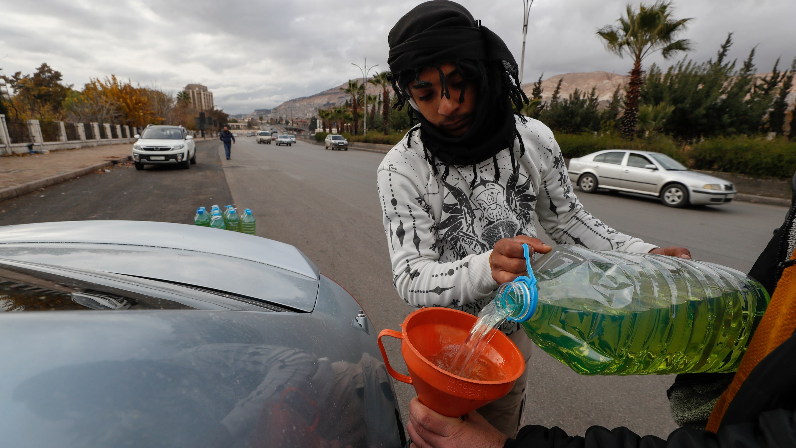 A street vendor fills up a car's tank with gasoline on a road in Damascus, Syria, Saturday, Dec. 28, 2024. (AP Photo/Omar Sanadiki)