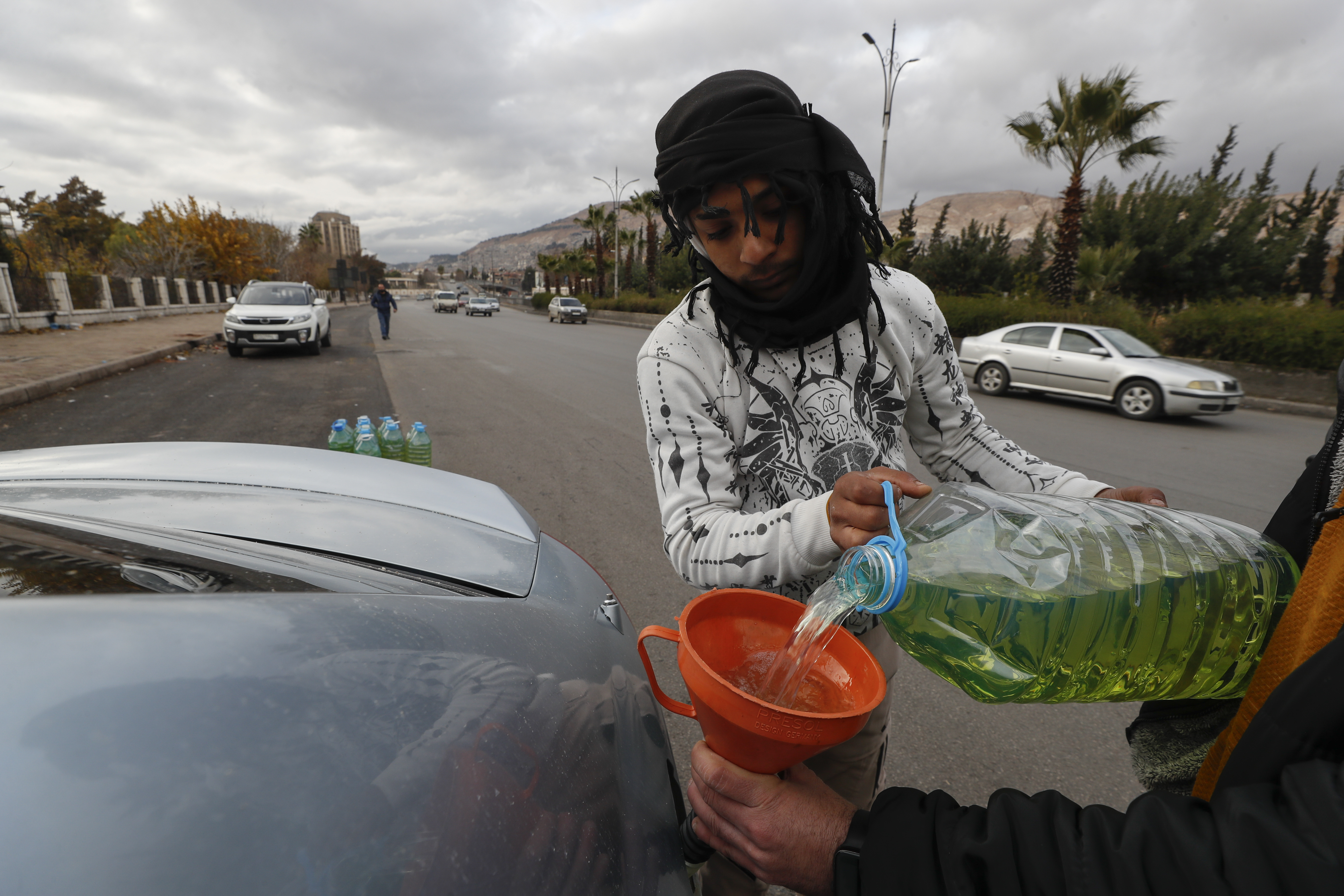 A street vendor fills up a car's tank with gasoline on a road in Damascus, Syria, Saturday, Dec. 28, 2024. (AP Photo/Omar Sanadiki)