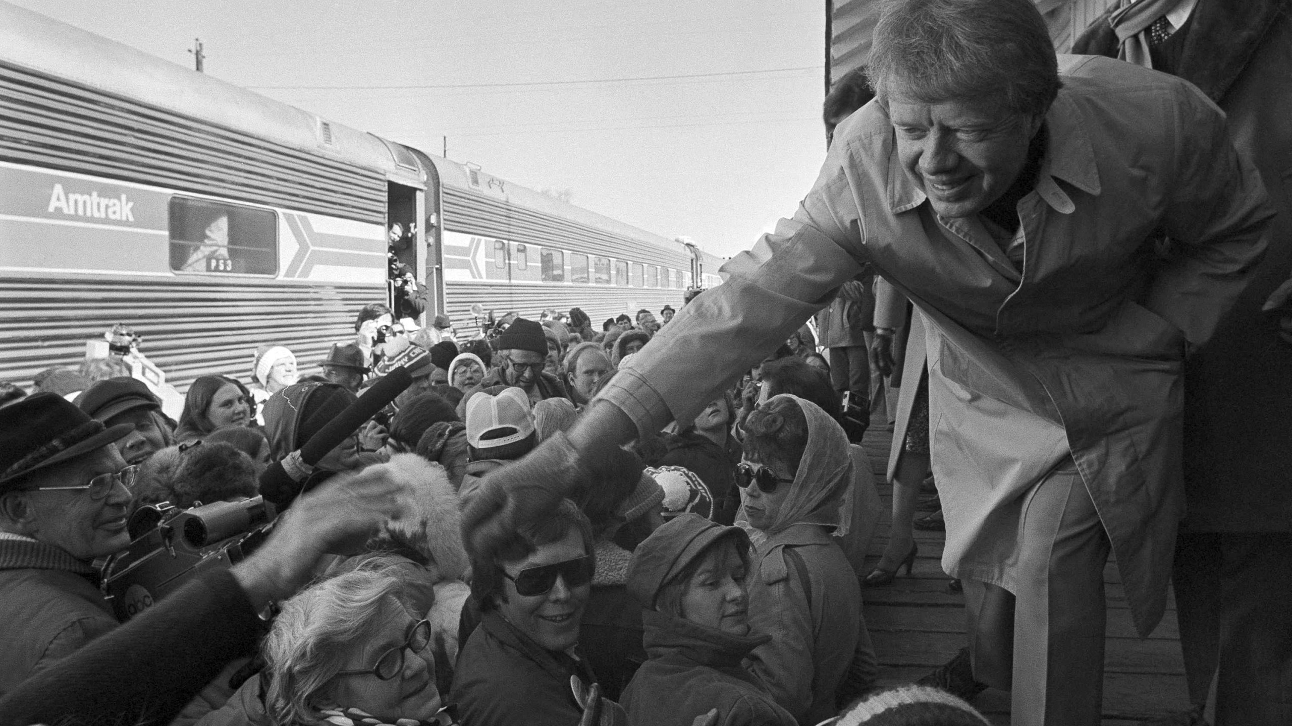 FILE - President-elect Jimmy Carter leans over to shake hands with some of the people riding the "Peanut Special" to Washington, Jan. 19, 1977. They will travel all night, arriving in Washington in time for Carter's inauguration as president on Jan. 20. (AP Photo, File)