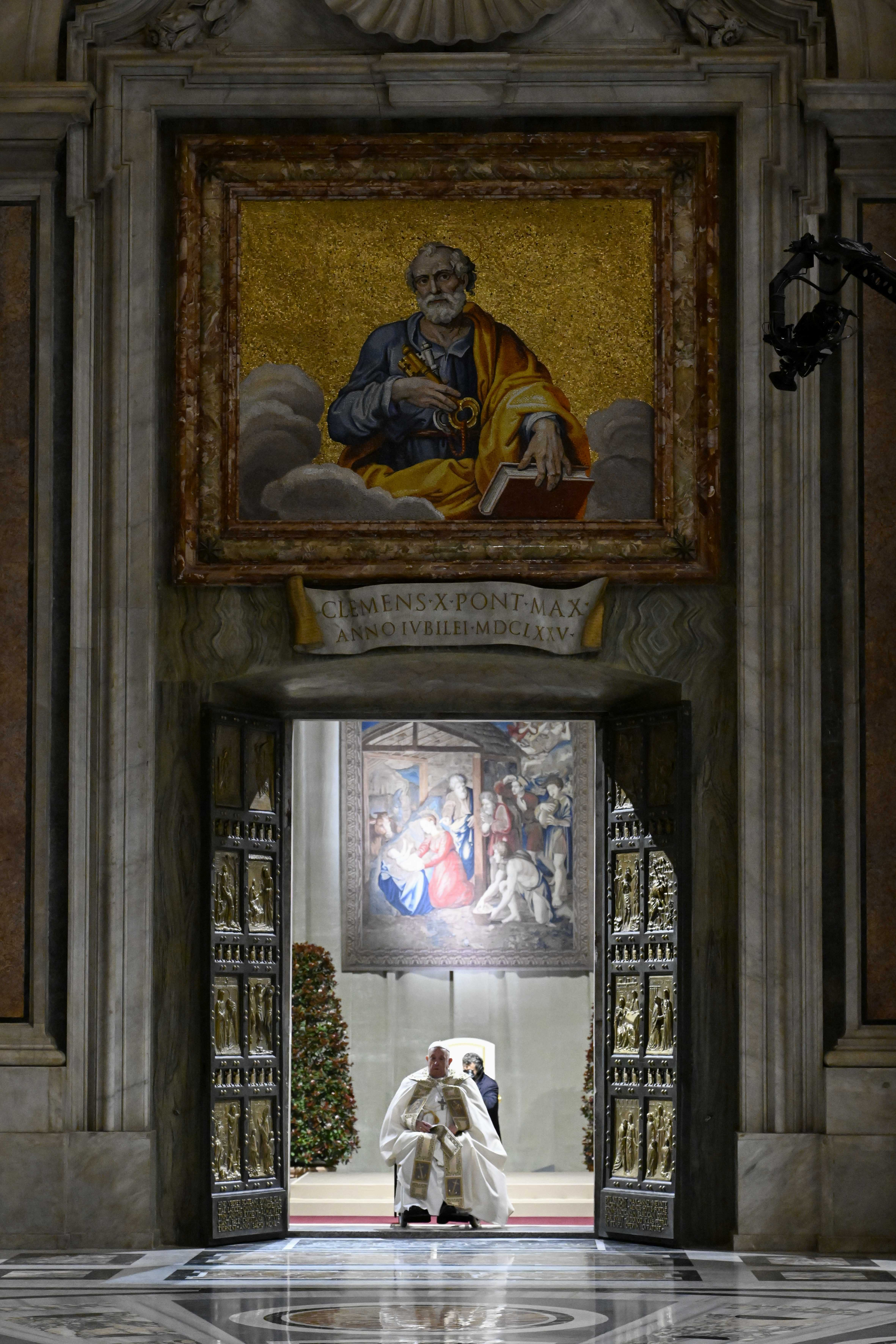 In this image released by Vatican Media, Pope Francis opens the holy door marking the start of the Catholic jubilar year 2025 before presiding over the Christmas Eve Mass in St. Peter's Basilica at The Vatican, Tuesday, Dec. 24, 2024. (AP Photo/Vatican Media, HO)