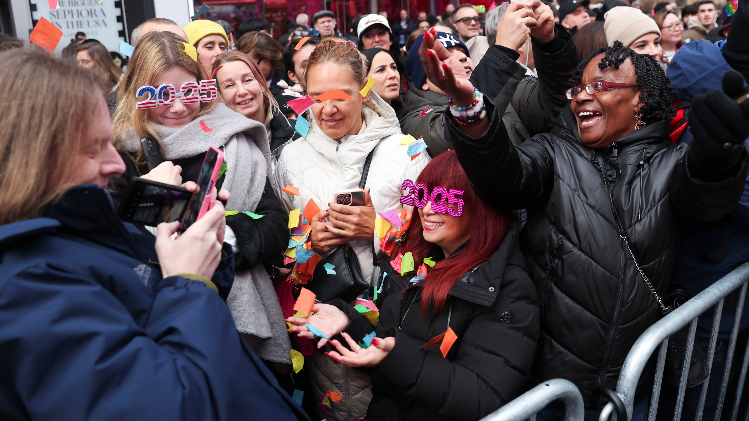 People in the crowd pose for photos with confetti ahead of New Year's Eve in Times Square, Sunday, Dec. 29, 2024, in New York. (AP Photo/Heather Khalifa)