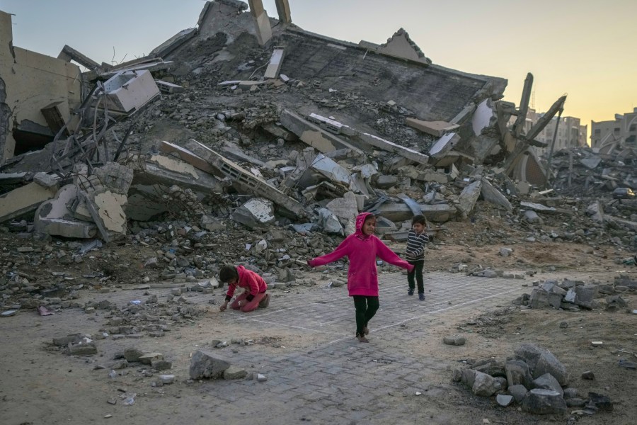 Palestinian children play next to a building destroyed by Israeli army strikes in the central Gaza Strip town of Khan Younis, Wednesday, Jan. 1, 2025. (AP Photo/Abdel Kareem Hana)