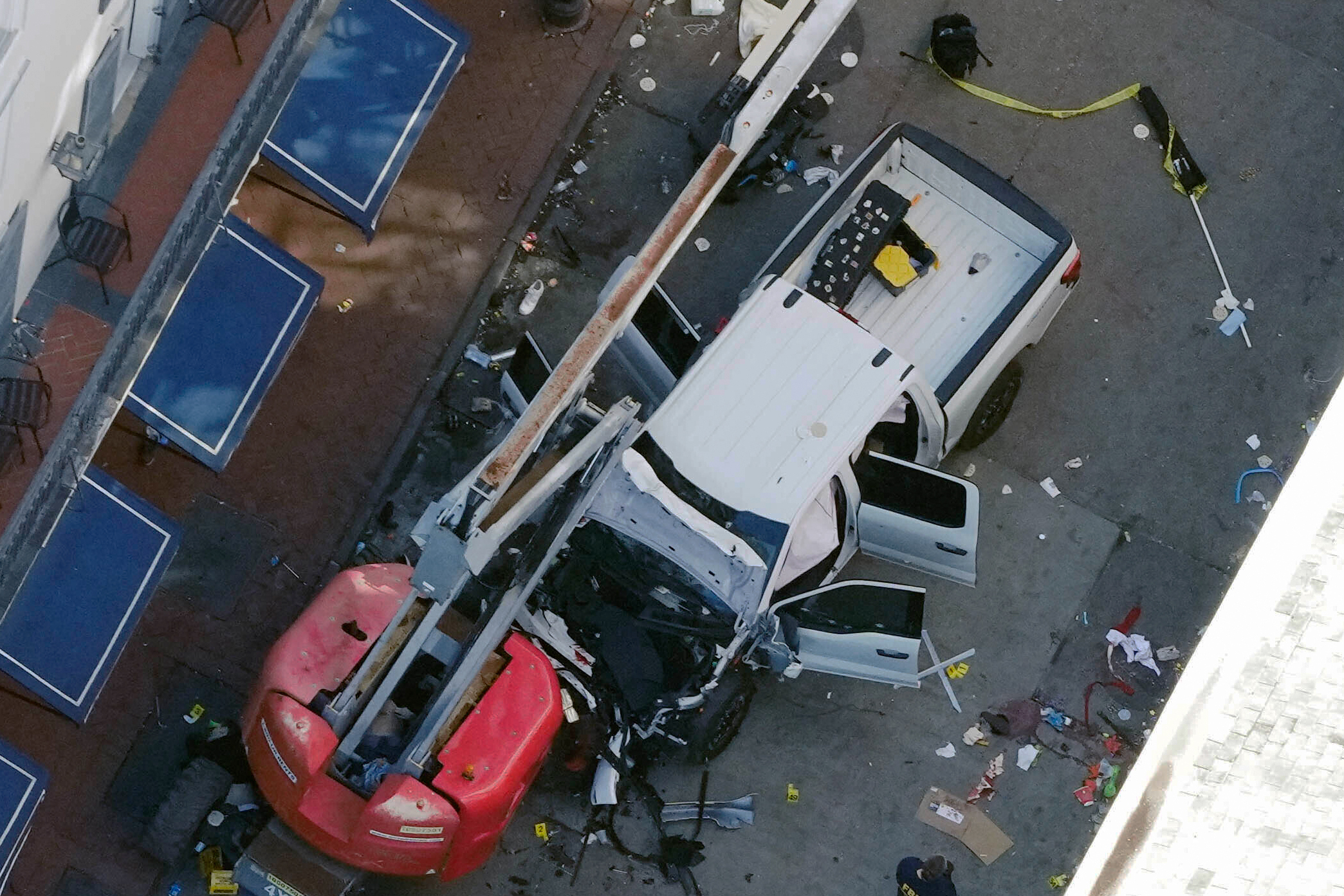 A black flag with white lettering lies on the ground rolled up behind a pickup truck that a man drove into a crowd on Bourbon Street in New Orleans, killing and injuring a number of people, early Wednesday morning, Jan. 1, 2025. The FBI said they recovered an Islamic State group flag, which is black with white lettering, from the vehicle. (AP Photo/Gerald Herbert)