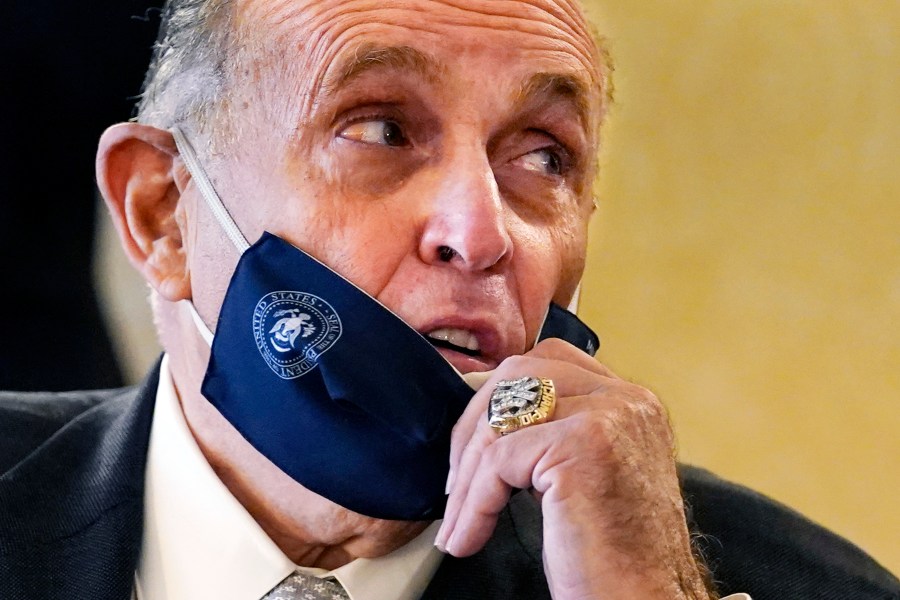 FILE — Former New York Mayor Rudy Giuliani, wearing a New York Yankees championship ring, pulls his face mask down to speak to an aide during a press conference at the Women's Republican Club, Sept. 16, 2020, in New York. (AP Photo/Kathy Willens, File)