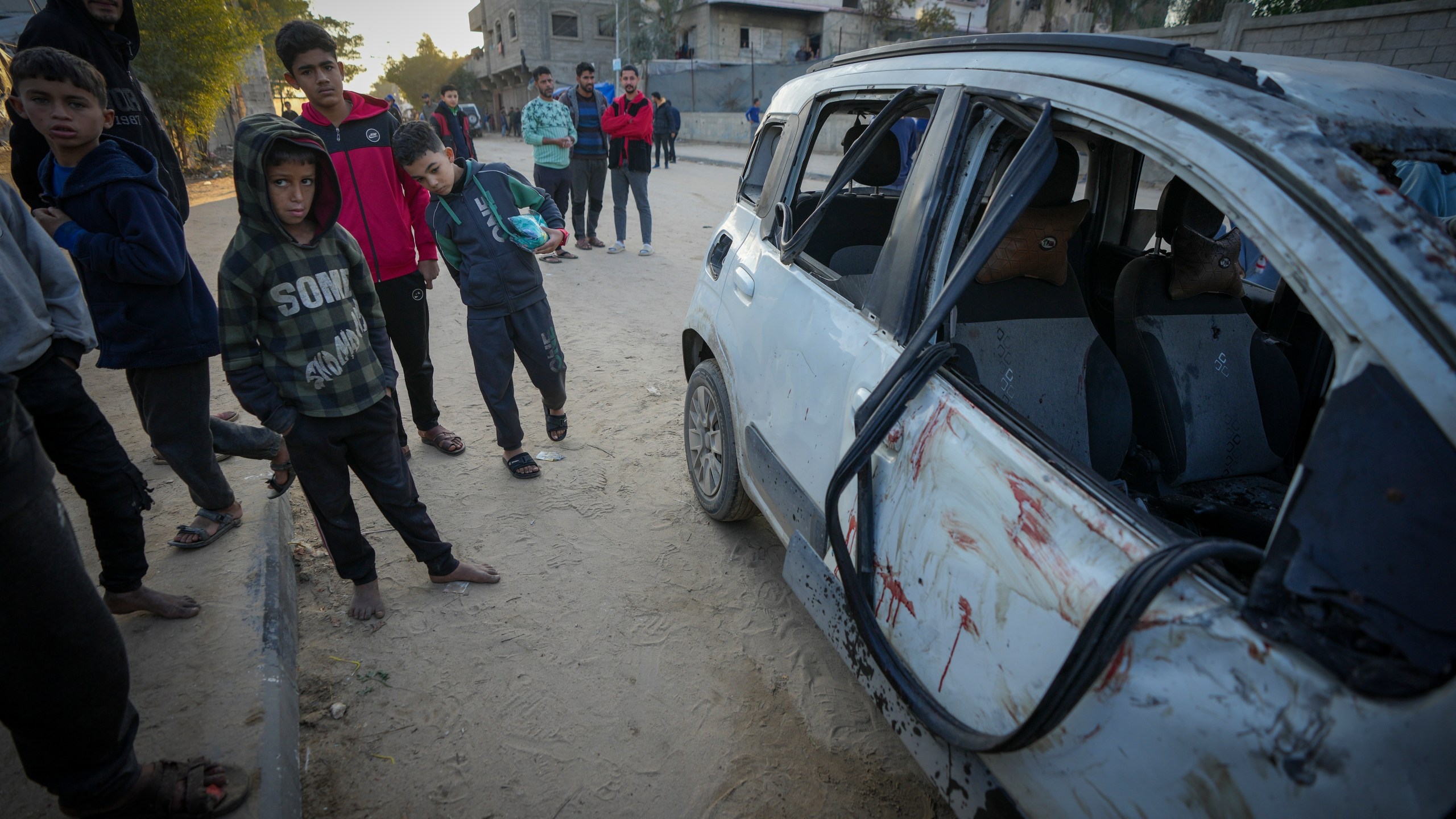 REMOVES NUMBER OF KILLED - Palestinian boys examine a car targeted in an Israeli army strike that killed several of its occupants in Deir al-Balah, central Gaza Strip, Friday, Jan. 3, 2025. (AP Photo/Abdel Kareem Hana)