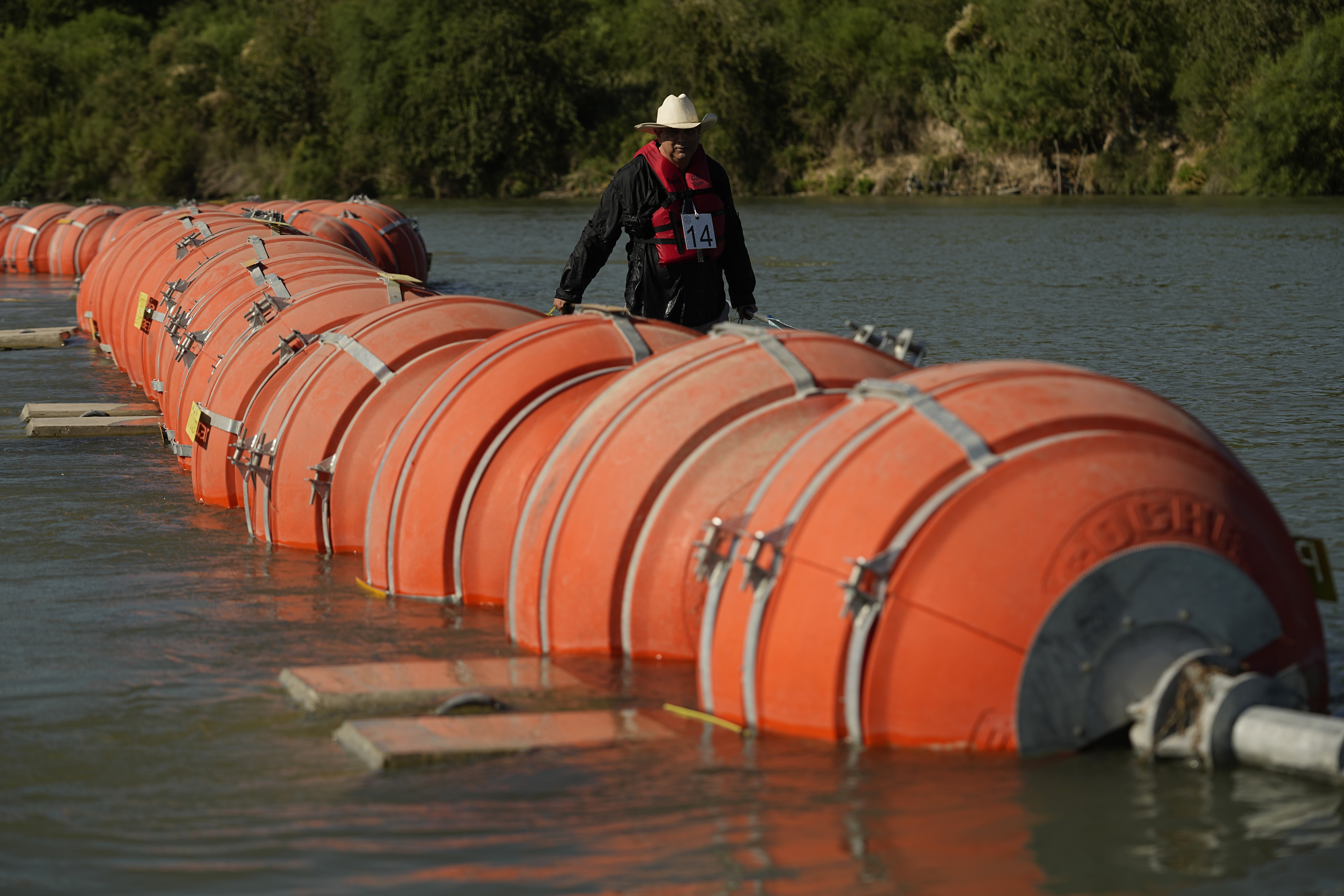 FILE - A kayaker walks past large buoys being used as a floating border barrier on the Rio Grande, Aug. 1, 2023, in Eagle Pass, Texas. (AP Photo/Eric Gay, File)