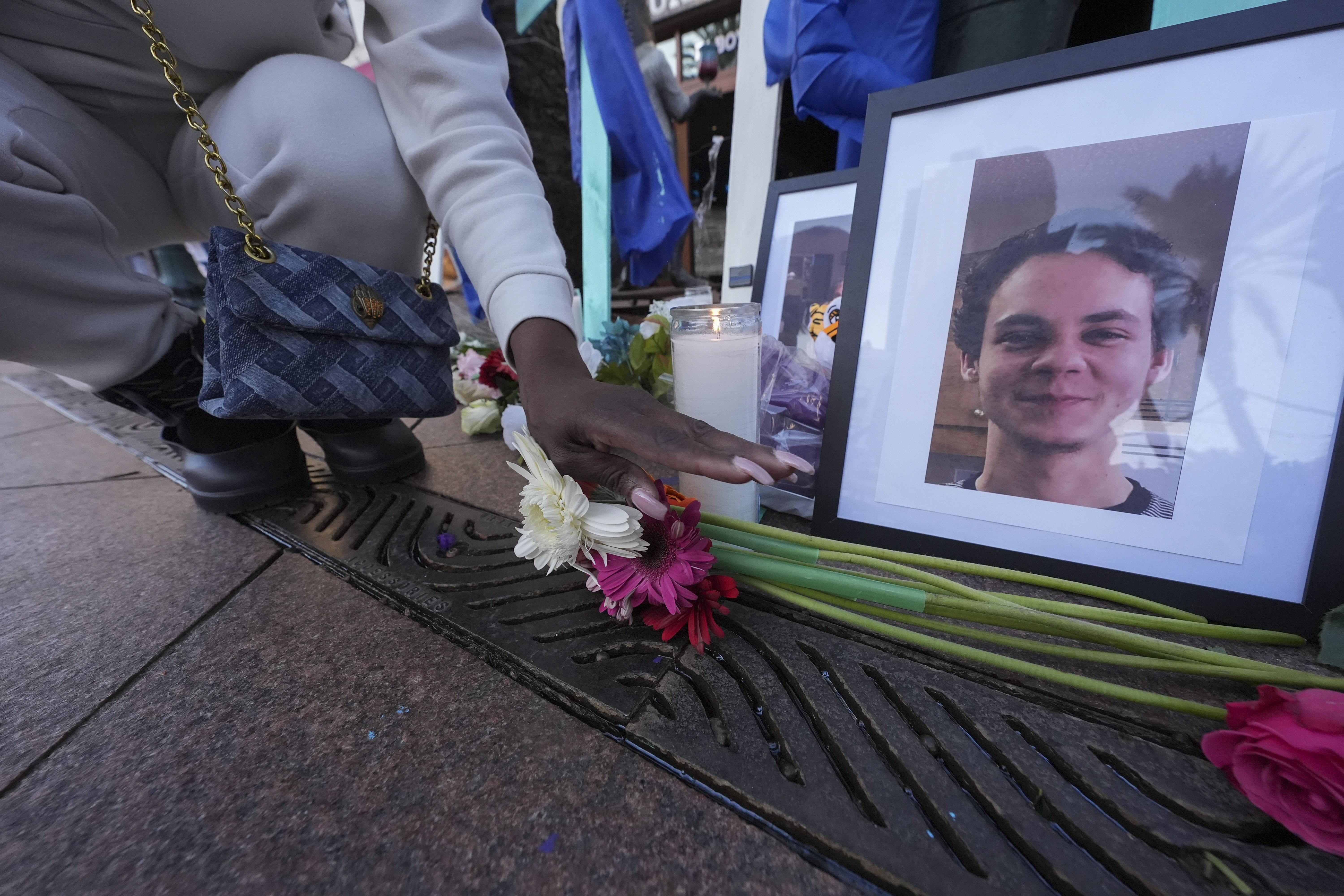 A woman places flowers next to photos of victim Matthew Tenedorio at memorial on Canal Street for the victims of a deadly truck attack on New Year's Day in New Orleans, Friday, Jan. 3, 2025. (AP Photo/Gerald Herbert)