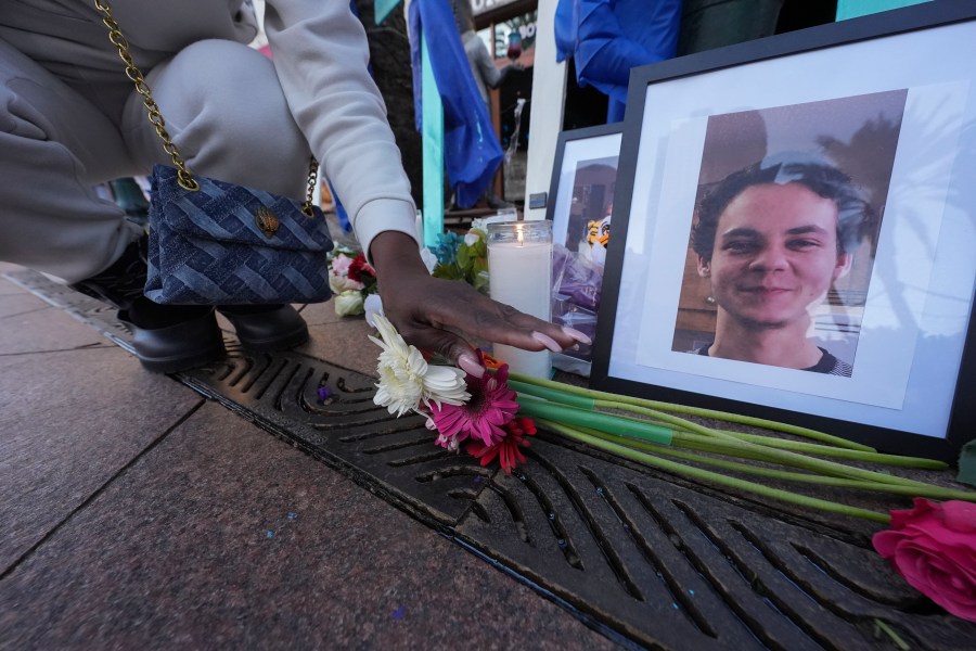 A woman places flowers next to photos of victim Matthew Tenedorio at memorial on Canal Street for the victims of a deadly truck attack on New Year's Day in New Orleans, Friday, Jan. 3, 2025. (AP Photo/Gerald Herbert)