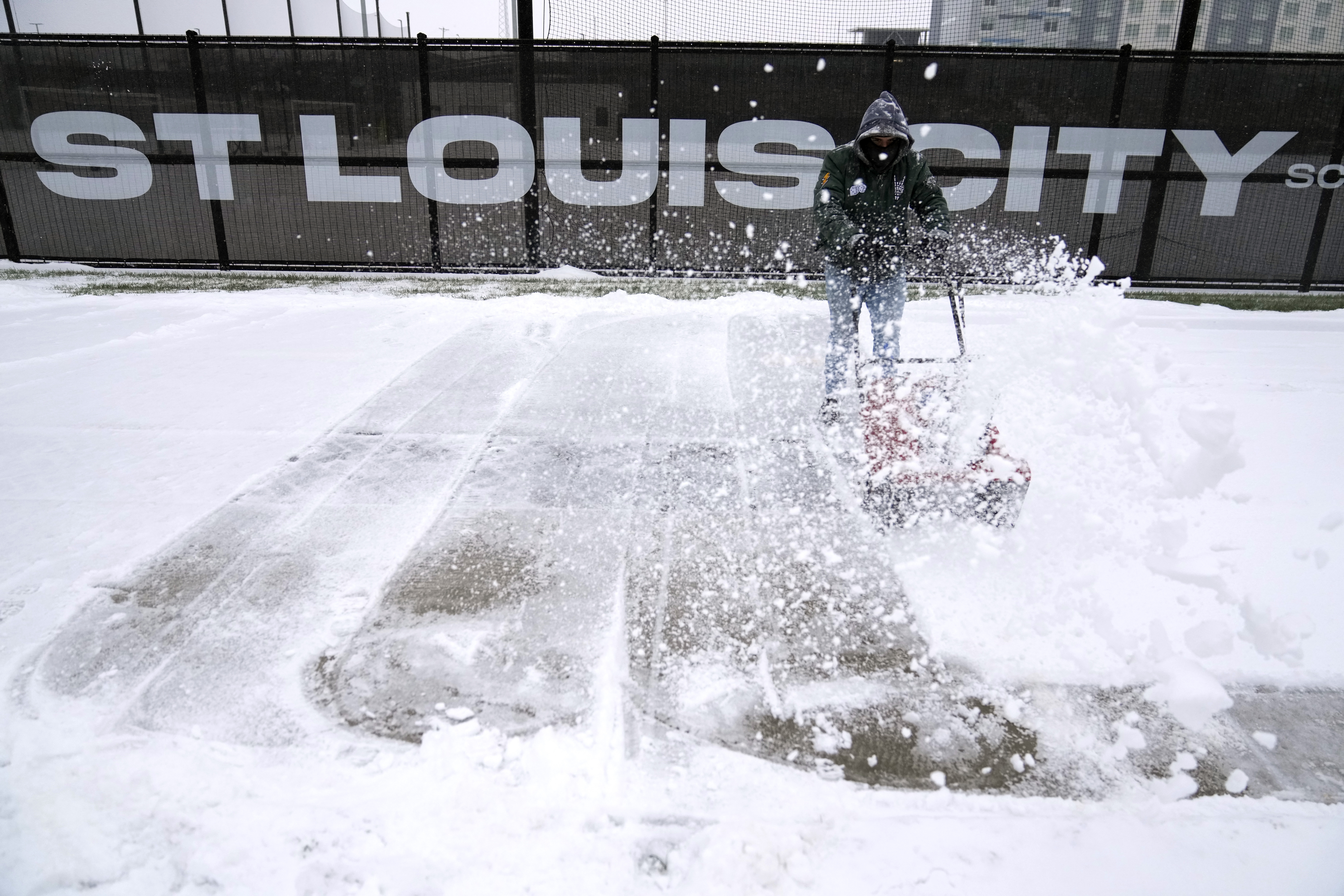 Andre Dresino uses a snow blower to clear a sidewalk Sunday, Jan. 5, 2025, in St. Louis. (AP Photo/Jeff Roberson)