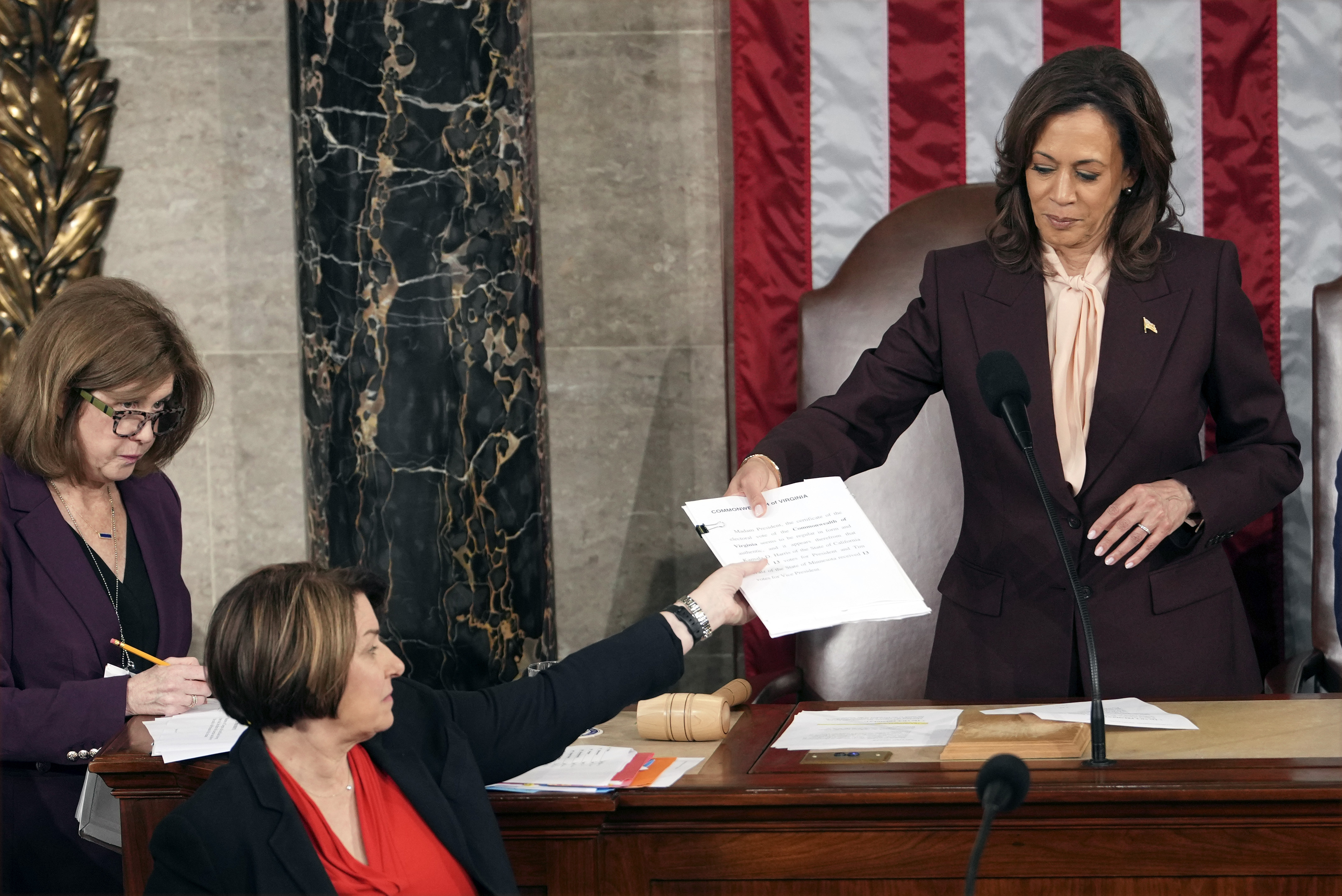 Vice President Kamala Harris hands the certification for Virginia to teller Sen. Amy Klobuchar, D-Minn., during joint session of Congress to confirm the Electoral College votes, affirming President-elect Donald Trump's victory in the presidential election, Monday, Jan. 6, 2025, at the U.S. Capitol in Washington. (AP Photo/Matt Rourke)