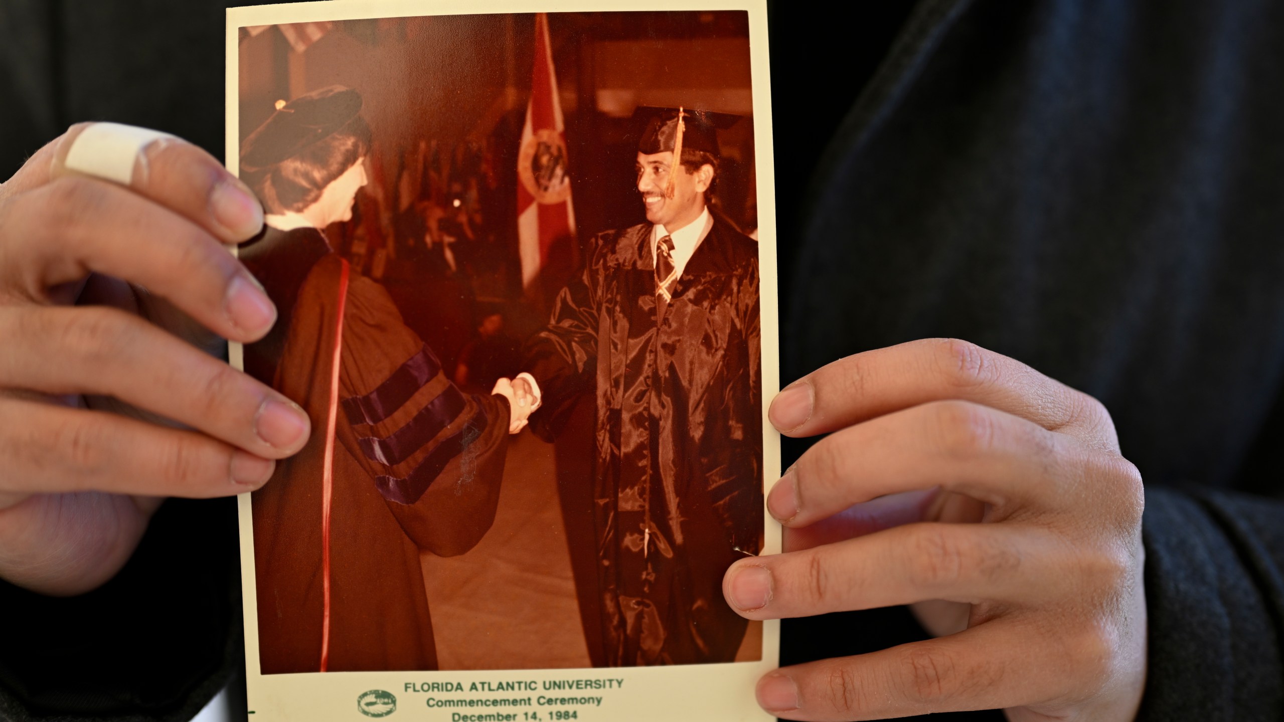 Ibrahim Almadi holds a photo of his father Saad Almadi graduating from college in 1984, in Washington Monday, Dec. 23, 2024. Saad Almadi, a dual U.S.-Saudi citizen was jailed for social media posts critical of the kingdom's crown prince. He was released from a Saudi prison in March 2023 and banned from returning to his home in south Florida. (AP Photo/John McDonnell)