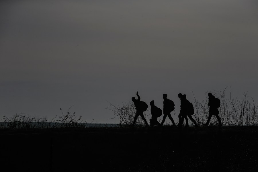 FILE - Migrants walk to enter Greece from Turkey by crossing the Maritsa river (Evros river in Greek) near the Pazarkule border gate in Edirne, Turkey, March 1, 2020. (AP Photo/Emrah Gurel, File)