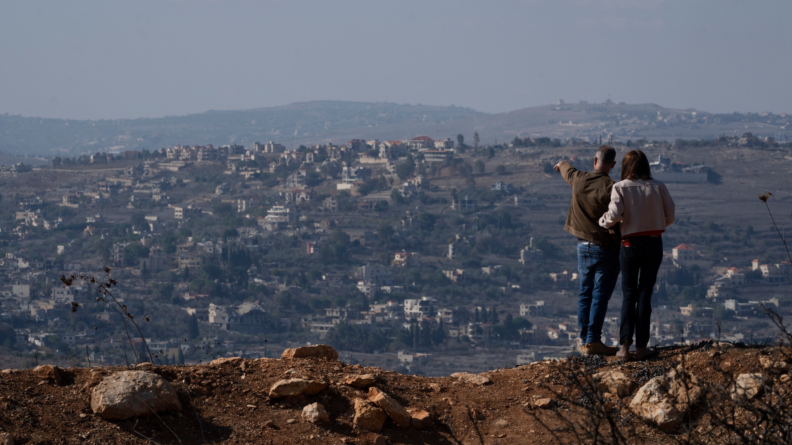 FILE - An Israeli couple can see buildings in southern Lebanon that were damaged during the war from an overlook in northern Israel, on Nov. 30, 2024. (AP Photo/Leo Correa, File)