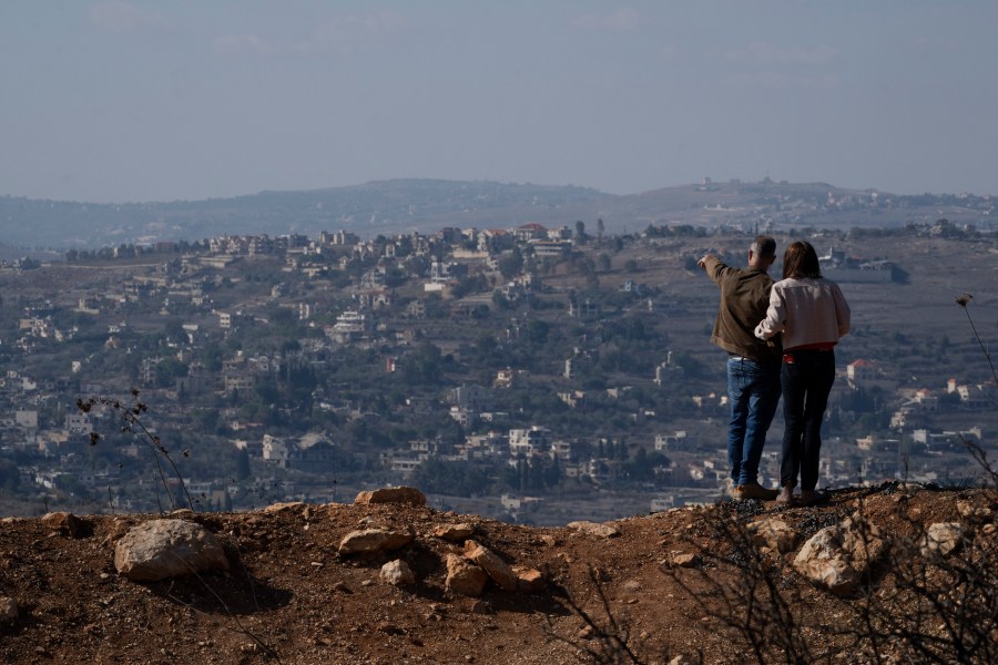 FILE - An Israeli couple can see buildings in southern Lebanon that were damaged during the war from an overlook in northern Israel, on Nov. 30, 2024. (AP Photo/Leo Correa, File)