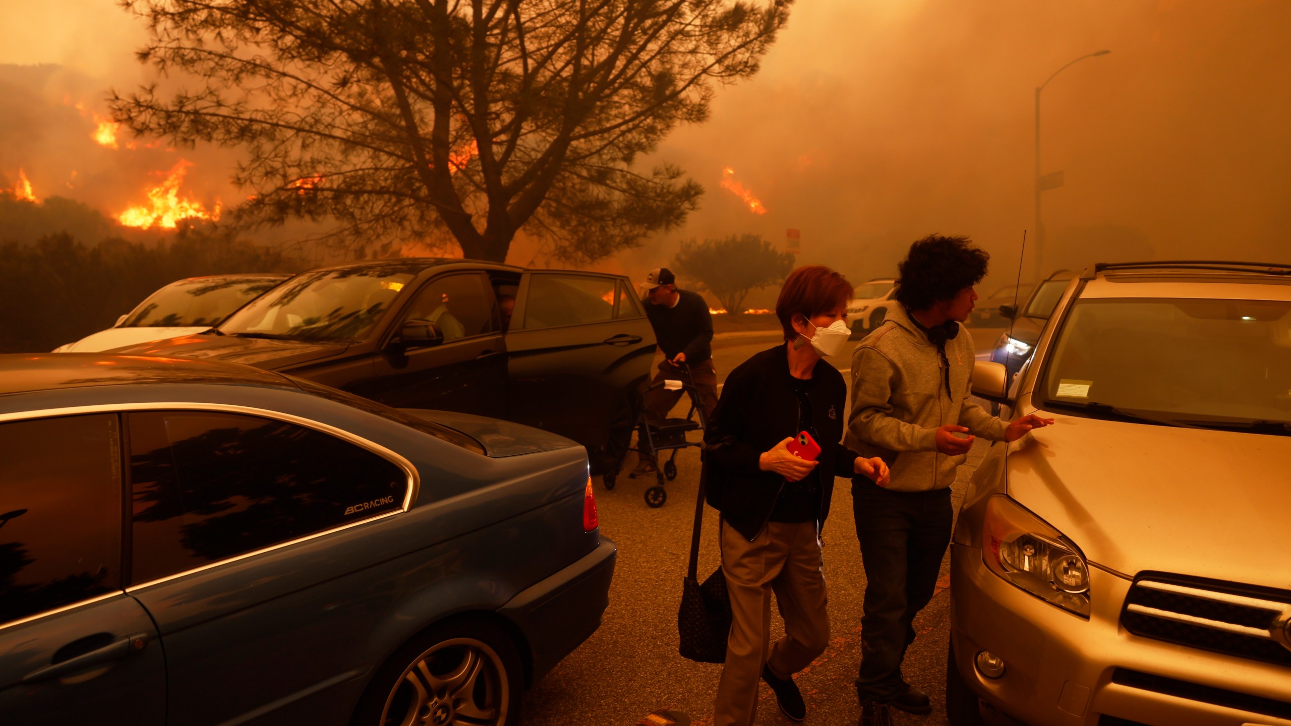 People flee from the advancing Palisades Fire, by car and on foot, in the Pacific Palisades neighborhood of Los Angeles Tuesday, Jan. 7, 2025. (AP Photo/Etienne Laurent)