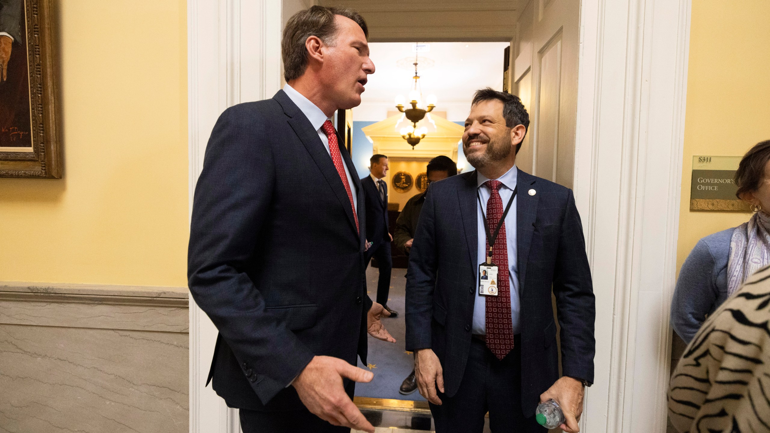 Virginia Gov. Glenn Youngkin, left, speaks to state Sen. Scott Surovell, D-Fairfax on the first day of the legislative session, Wednesday, Jan. 8, 2025, in Richmond, Va. (Mike Kropf/Richmond Times-Dispatch via AP)