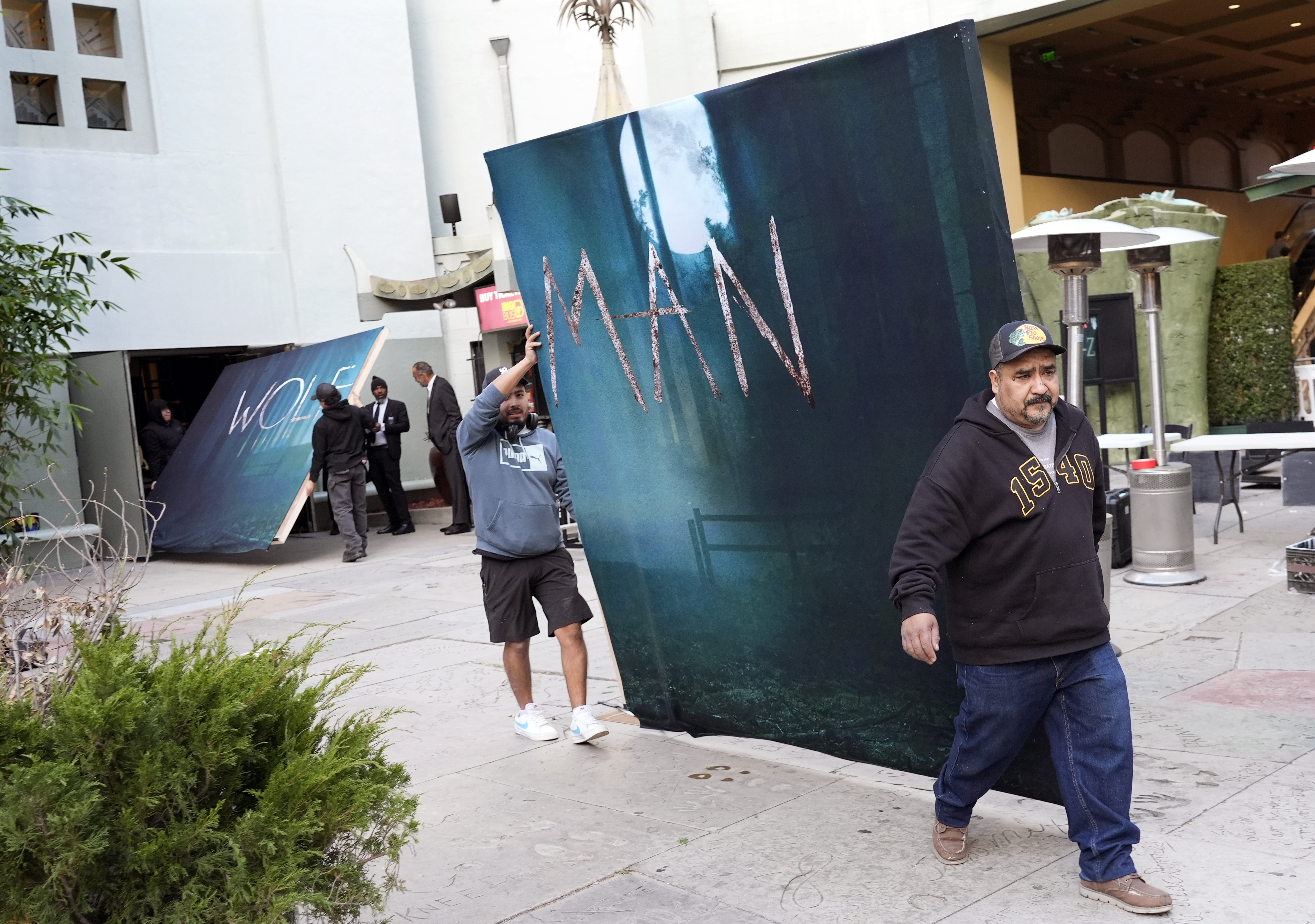 Crew members carry out signs for the new film "Wolf Man" after the premiere was cancelled due to high winds in the area on Tuesday, Jan. 7, 2025, at the TCL Chinese Theatre in Los Angeles. (AP Photo/Chris Pizzello)