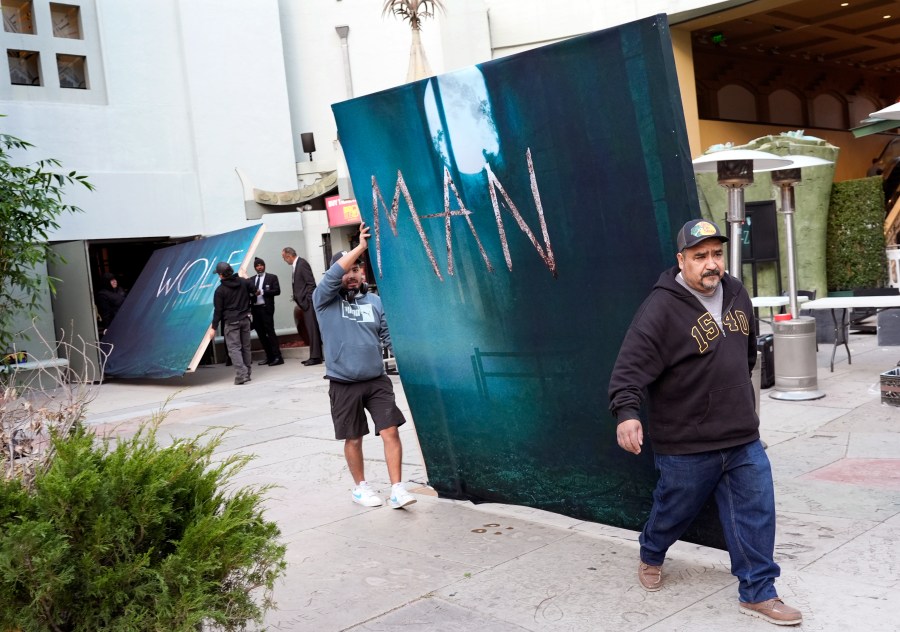 Crew members carry out signs for the new film "Wolf Man" after the premiere was cancelled due to high winds in the area on Tuesday, Jan. 7, 2025, at the TCL Chinese Theatre in Los Angeles. (AP Photo/Chris Pizzello)