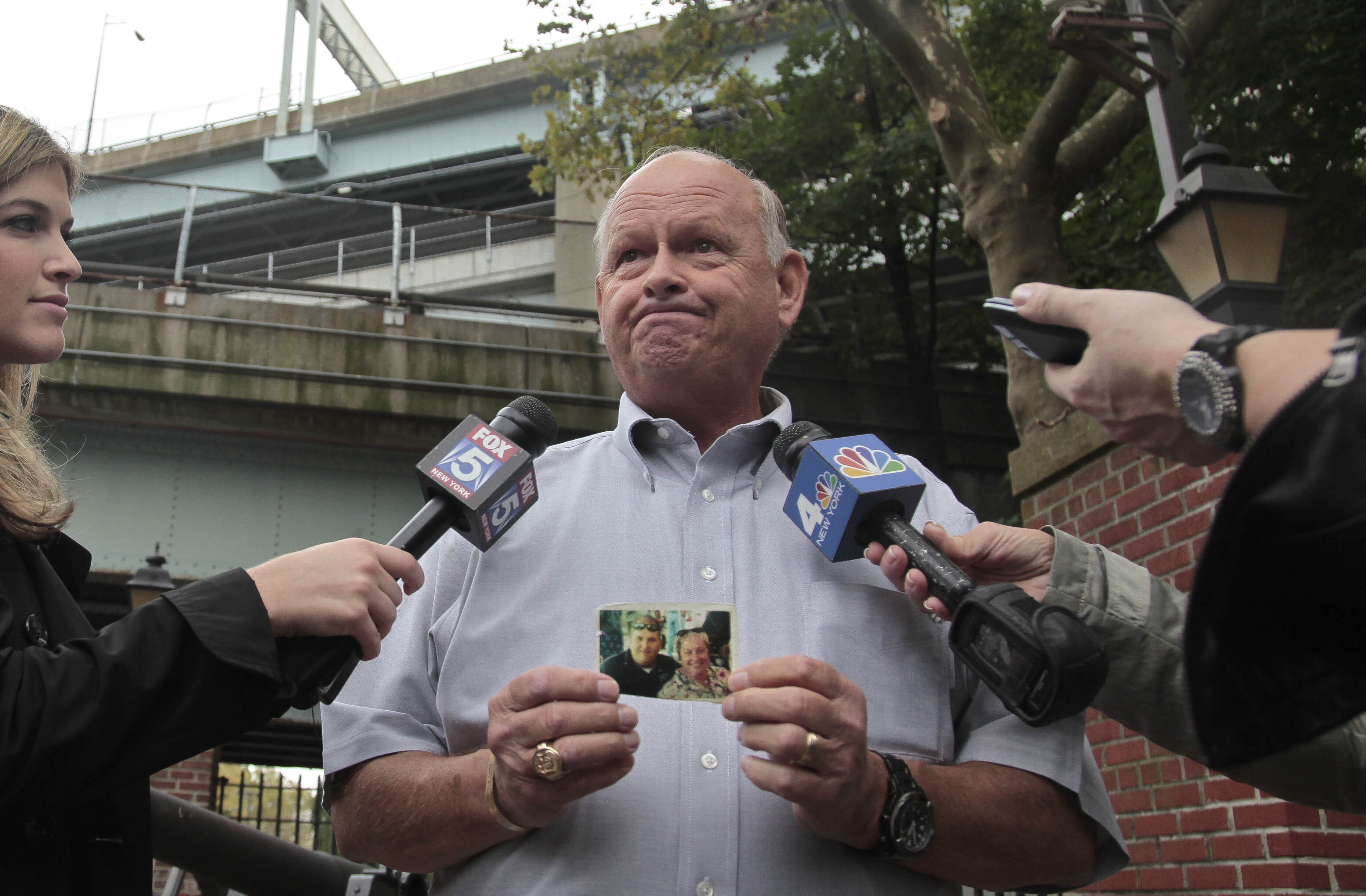 FILE - Ken Fairben holds a photo showing his son Keith, left, a victim of the Sept, 11, attacks, as he talks with reporters Oct. 15, 2012, outside Fort Hamilton Army base in Brooklyn, N.Y. (AP Photo/Bebeto Matthews, File)