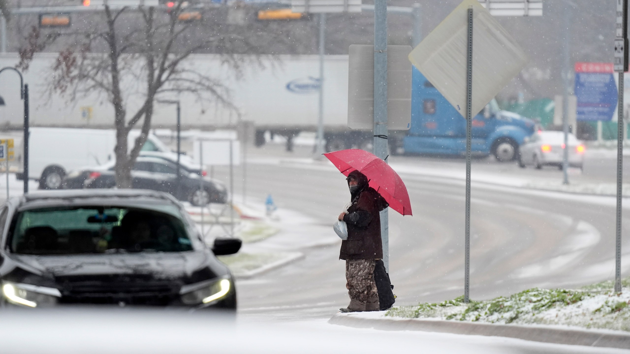 A man who gave his name as Servo uses an umbrella to cross a street as snow falls Thursday, Jan. 9, 2025, in Dallas. (AP Photo/LM Otero)