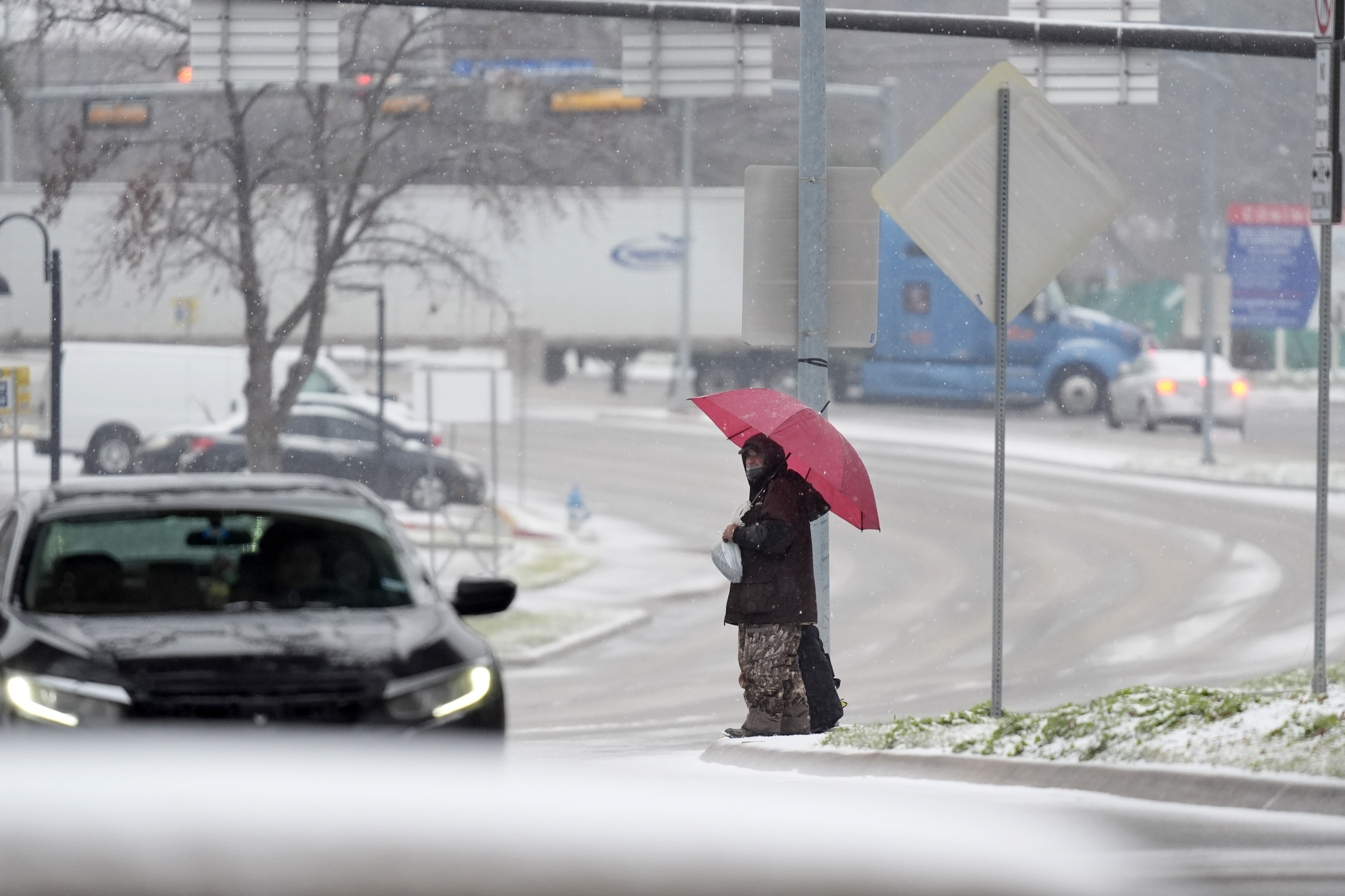 A man who gave his name as Servo uses an umbrella to cross a street as snow falls Thursday, Jan. 9, 2025, in Dallas. (AP Photo/LM Otero)