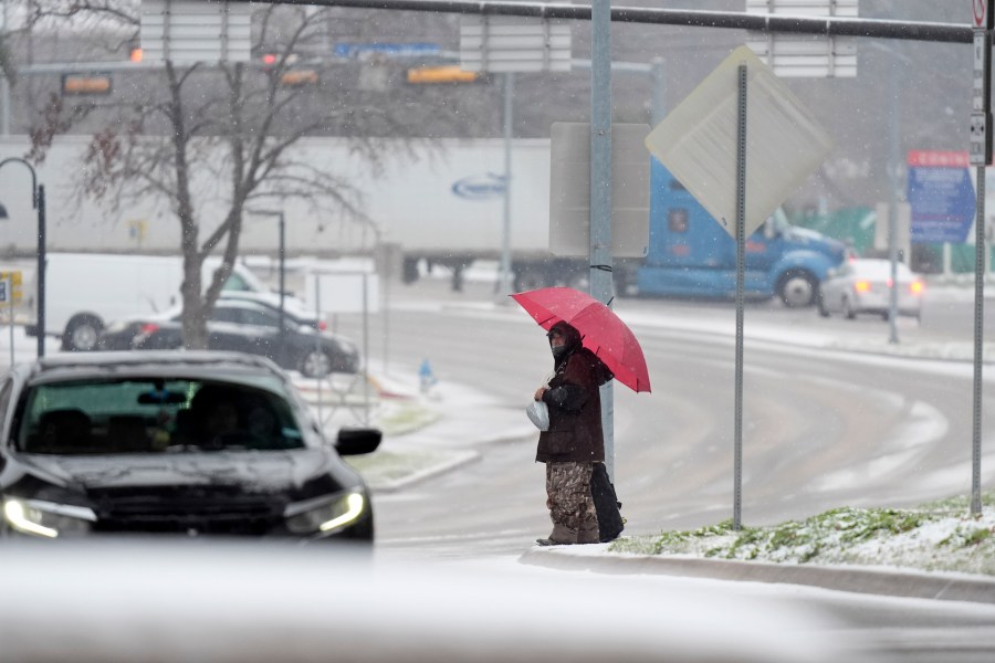 A man who gave his name as Servo uses an umbrella to cross a street as snow falls Thursday, Jan. 9, 2025, in Dallas. (AP Photo/LM Otero)