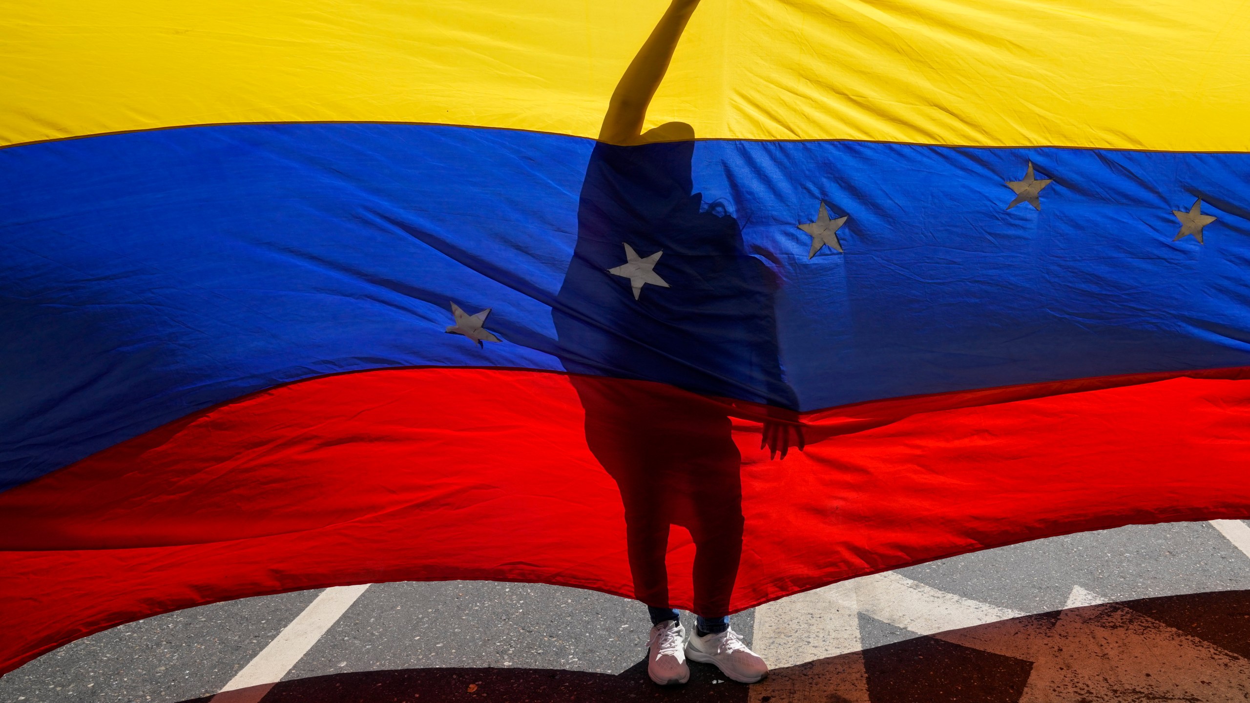 Opponents of Venezuelan President Nicolas Maduro display a Venezuelan flag during a protest the day before his inauguration for a third term in Caracas, Venezuela, Thursday, Jan. 9, 2025. (AP Photo/Ariana Cubillos)