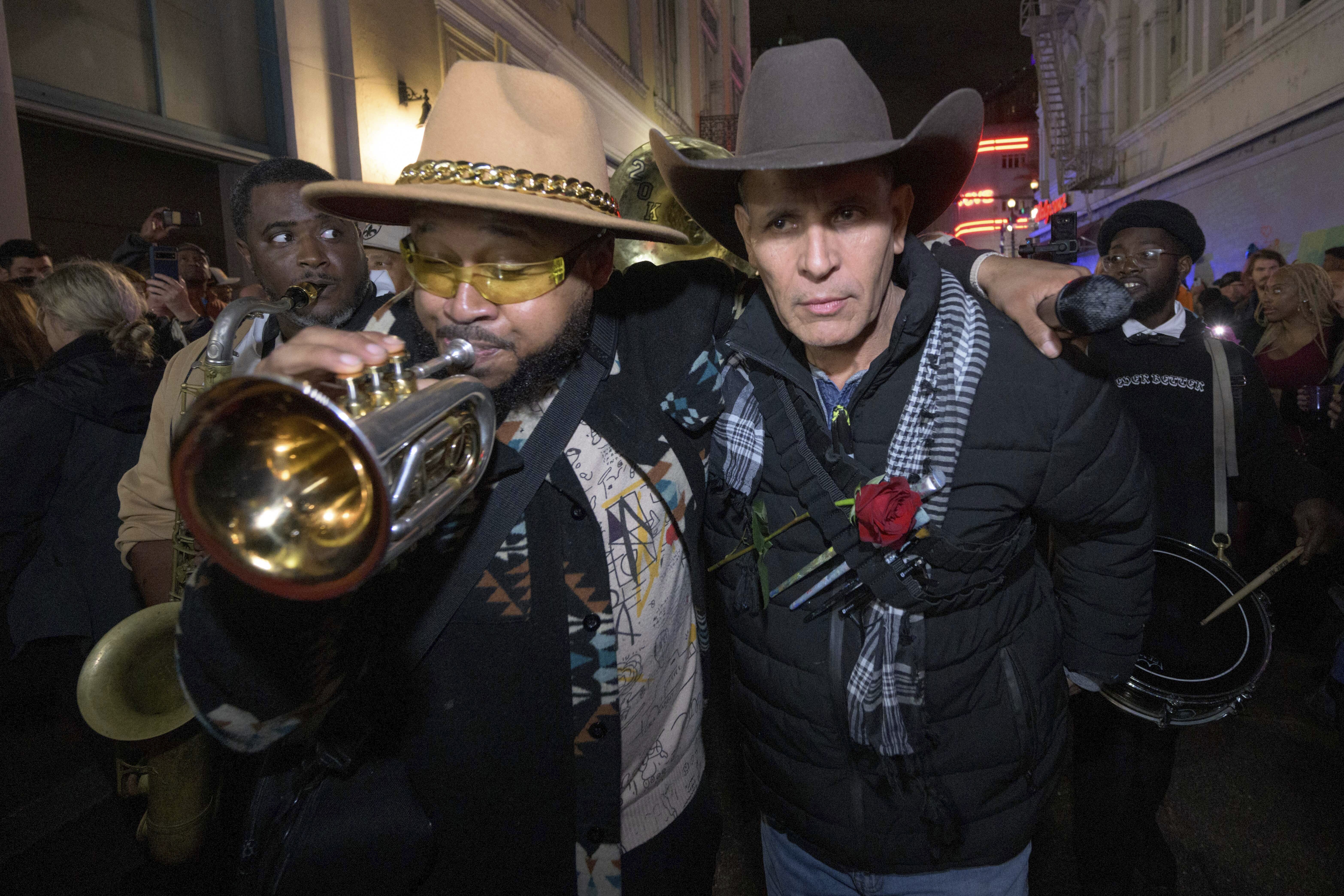 Amir "Tubad" Gray, left, leads Tubad and the Kings of NOLA Brass Band and artist Roberto Marquez, right, in New Orleans, Saturday, Jan. 4, 2025, as they memorialize the victims of the New Year's Day deadly truck attack and shooting. Marquez organized the parade and vigil and designed a memorial for the victims on Bourbon Street. (AP Photo/Matthew Hinton)