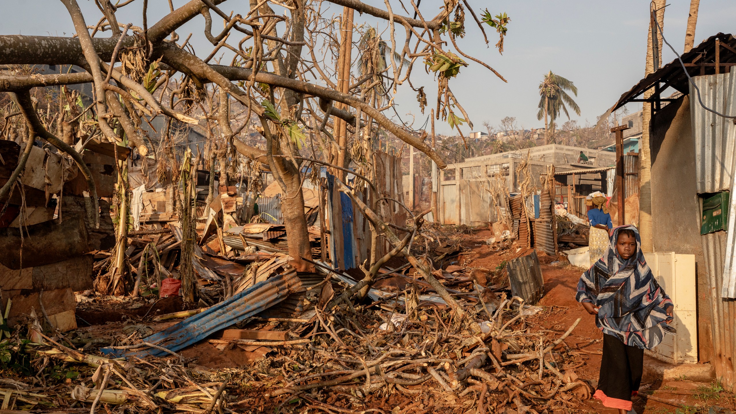 A girl walks amidst destruction in Mbouyougou, Mayotte, Saturday, Dec. 21, 2024. (AP Photo/Adrienne Surprenant)