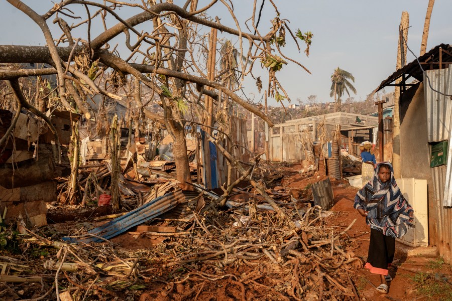 A girl walks amidst destruction in Mbouyougou, Mayotte, Saturday, Dec. 21, 2024. (AP Photo/Adrienne Surprenant)