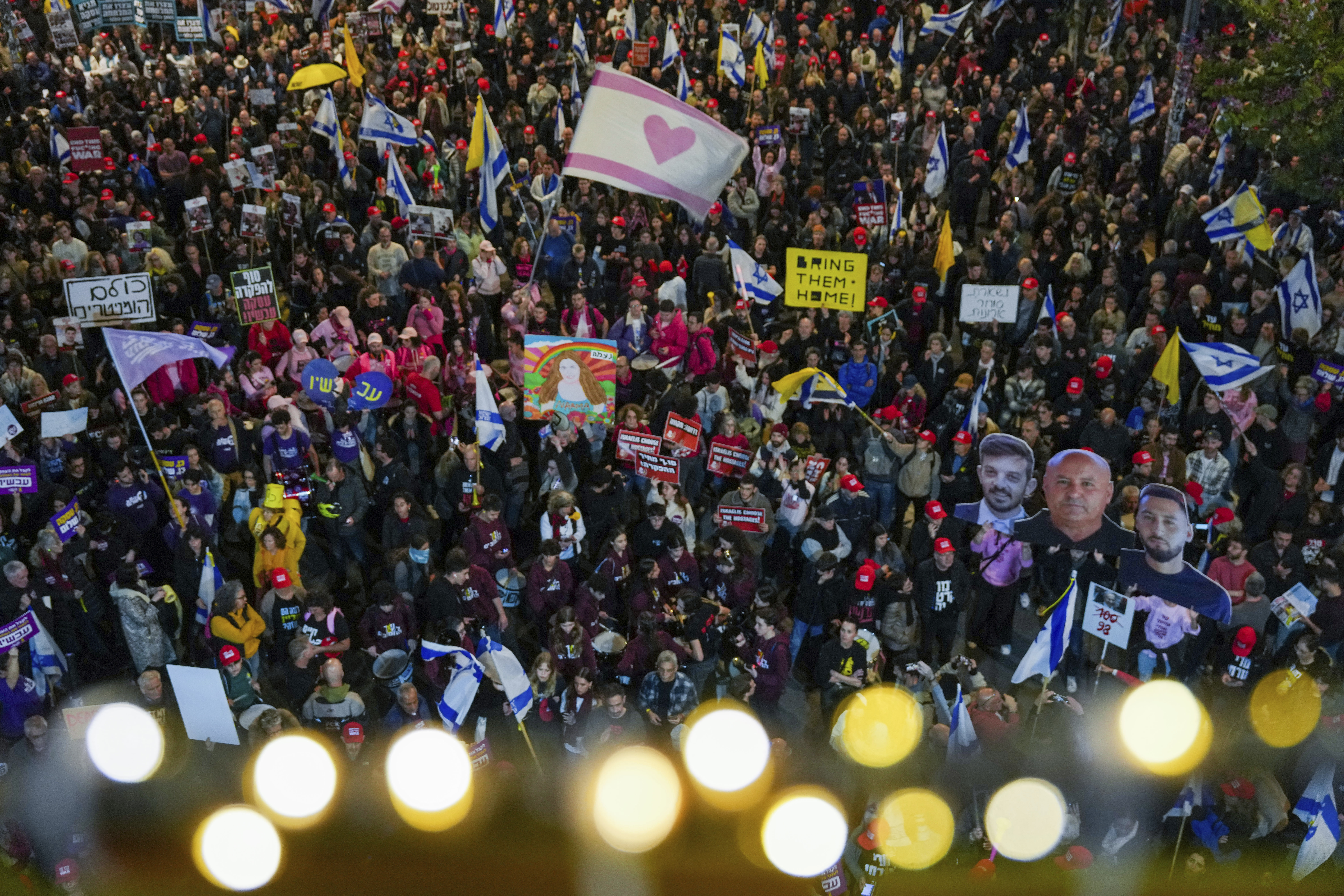 Demonstrators wave Israeli flags and signs during a protest calling for the immediate release of the hostages held in the Gaza Strip by Hamas militant group, in Tel Aviv, Israel, Saturday, Jan. 11, 2025. (AP Photo/Ariel Schalit)