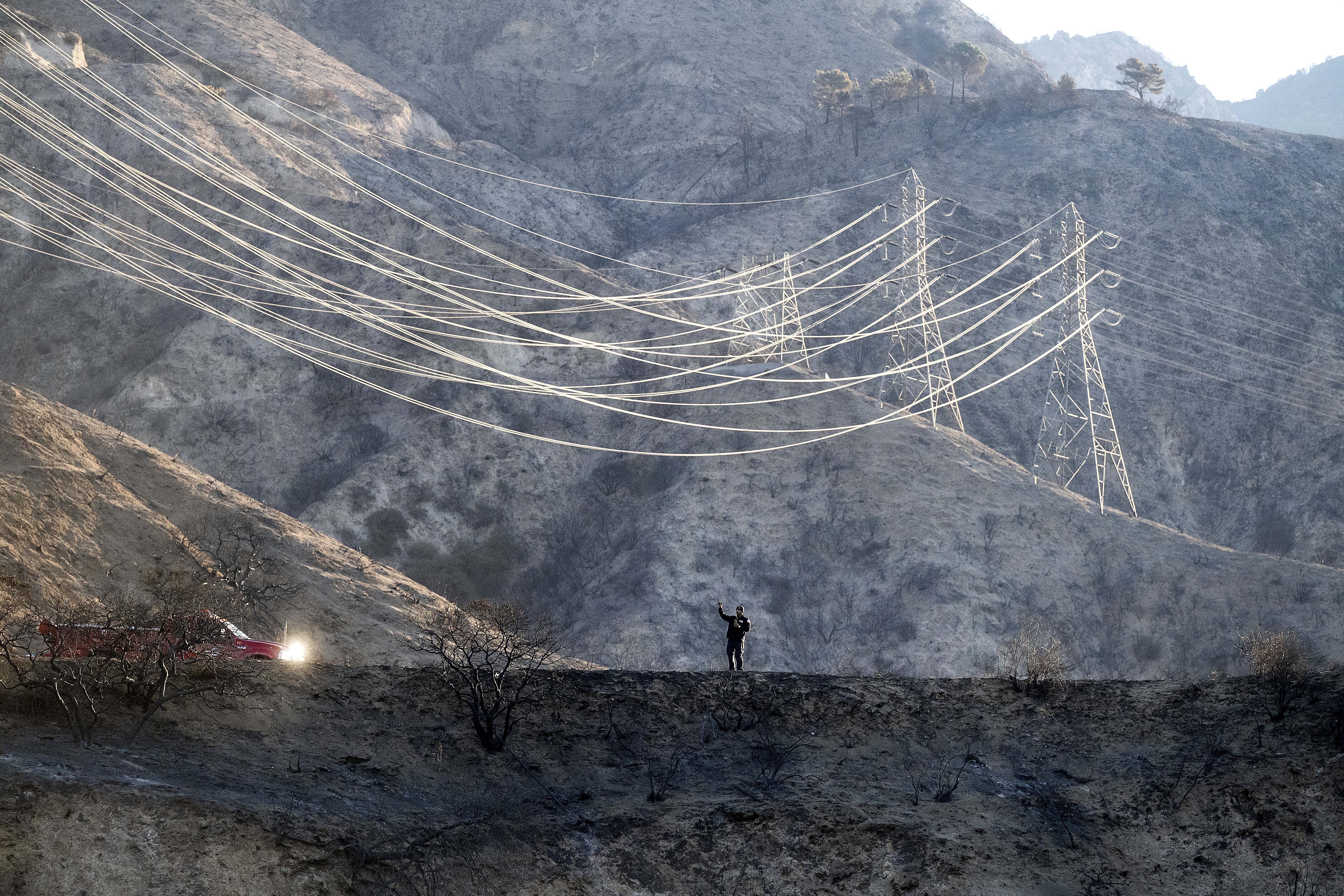 A firefighter takes weather readings while standing on a scorched ridgetop above the Eaton Fire in Angeles National Forest on Monday, Jan. 13, 2025. (AP Photo/Noah Berger)