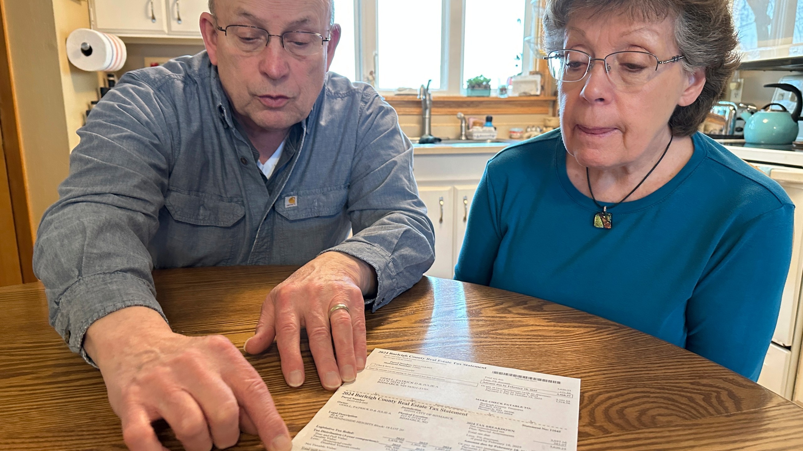 Pat and Julie O'Dell point out details of their property tax statement in their home in Bismarck, N.D., on Friday, Jan. 10, 2025. (AP Photo/Jack Dura)